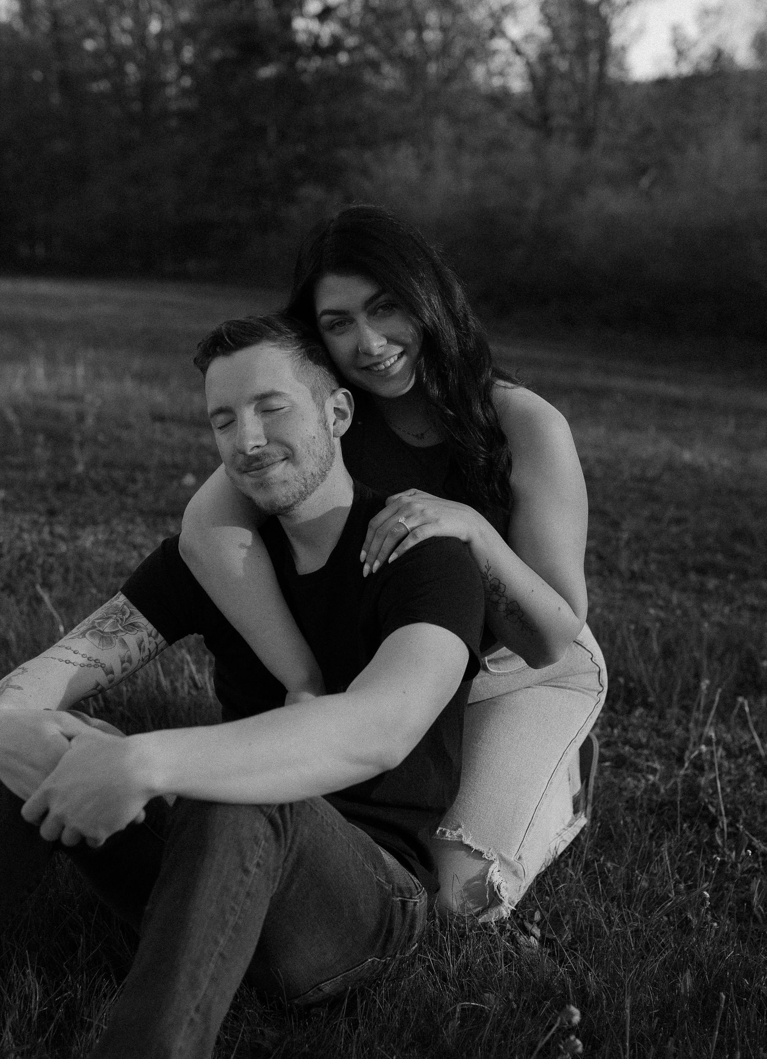 Black and white series showing tender moments between a couple sitting in a field.