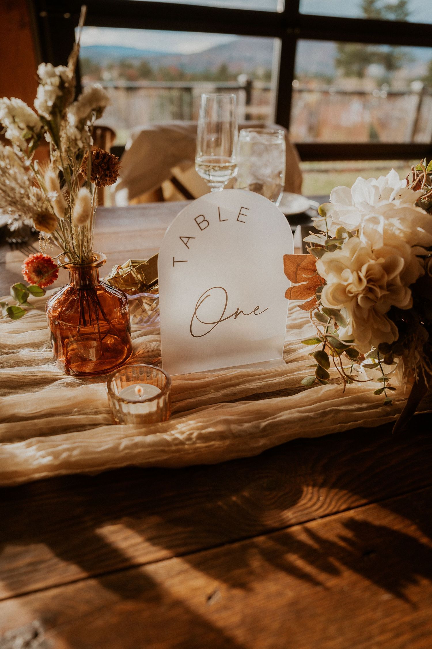 Elegant wedding table settings with rustic wooden tables, delicate place cards, and soft floral arrangements in warm lighting.