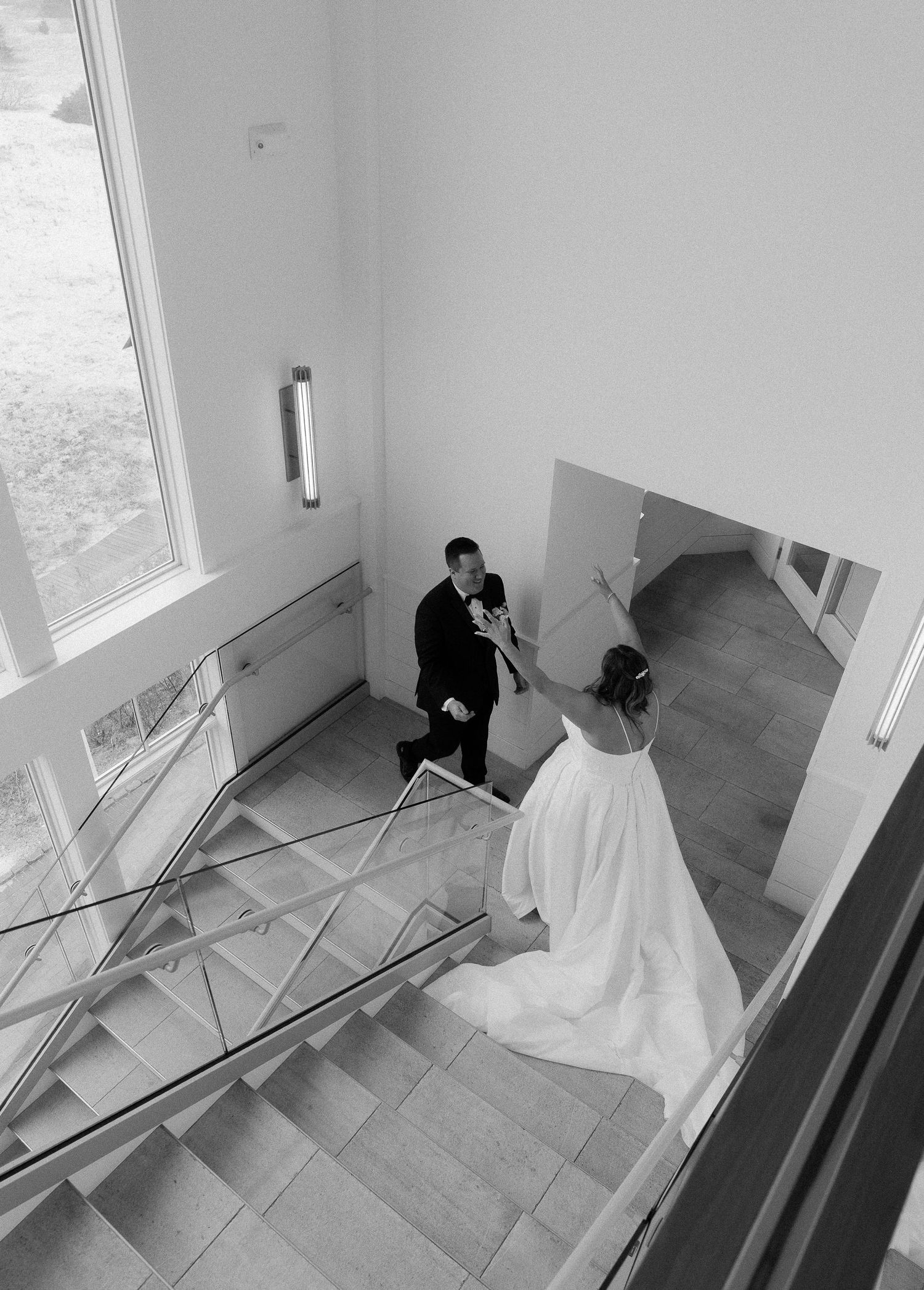 Black and white aerial photo of bride and groom sharing a romantic moment on an elegant staircase.