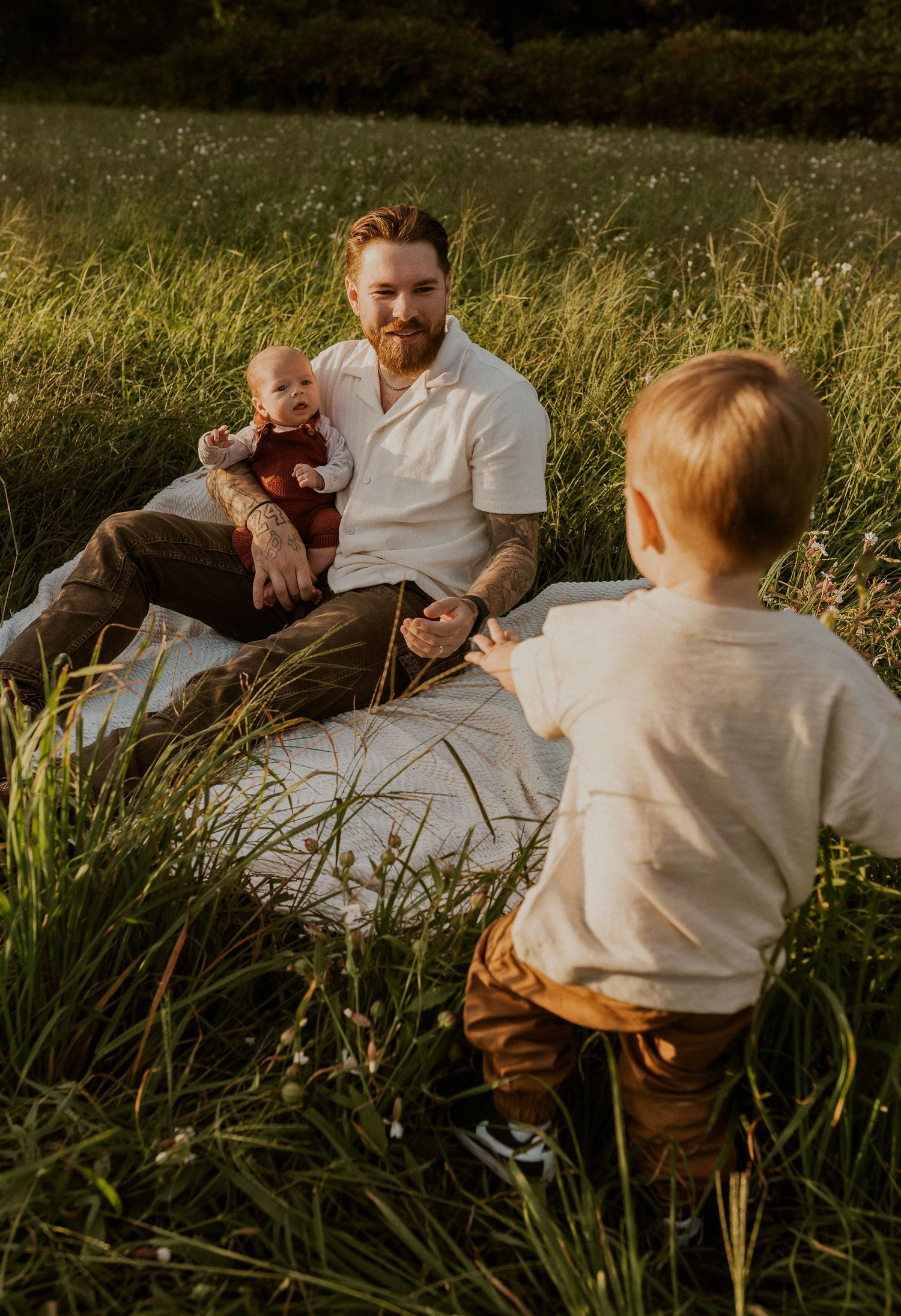 Family sharing tender moments together on blanket in grass field.