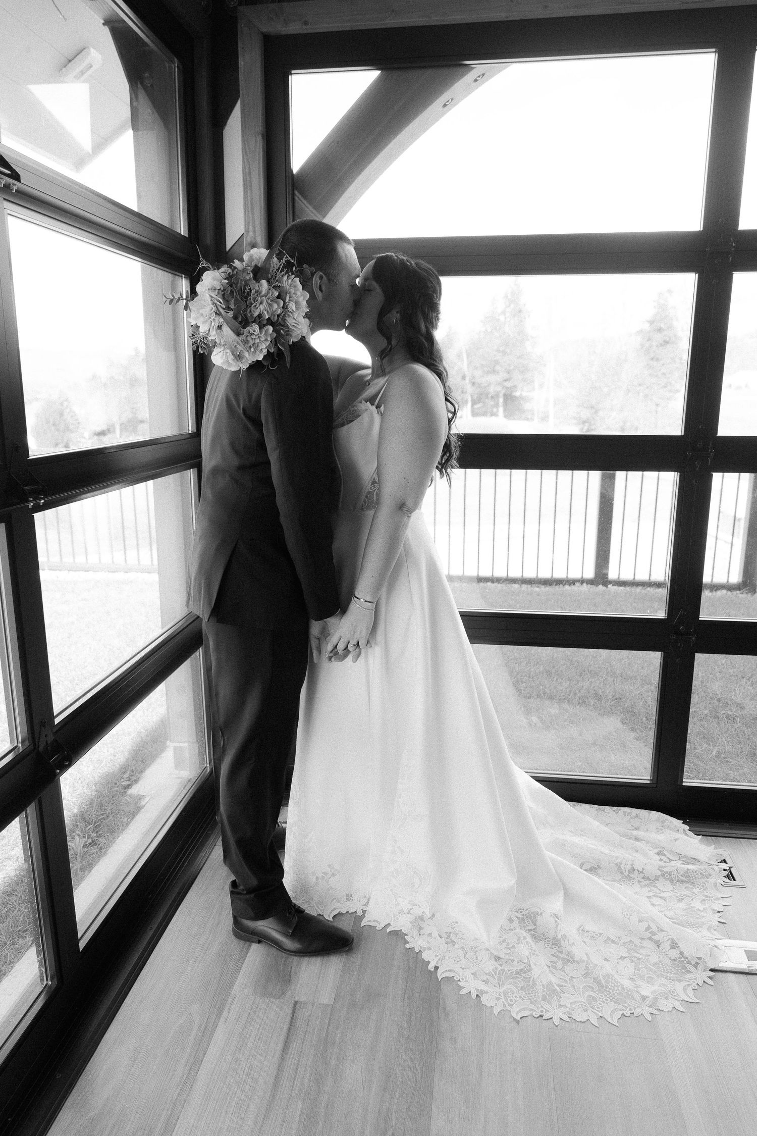 Black and white wedding photos in a contemporary venue with dramatic window lighting.