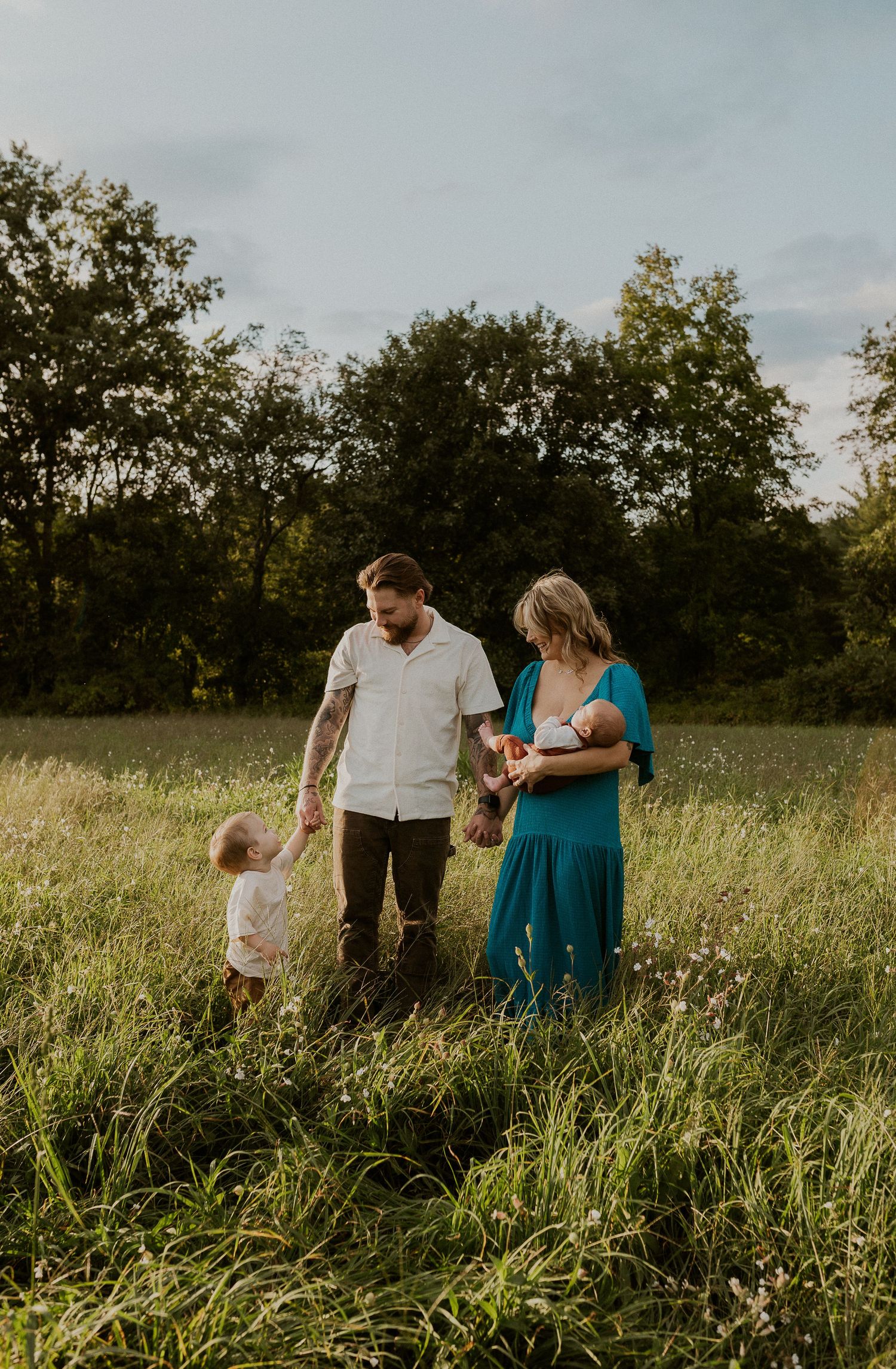 Family enjoying time together in a sunlit meadow with tall grass.