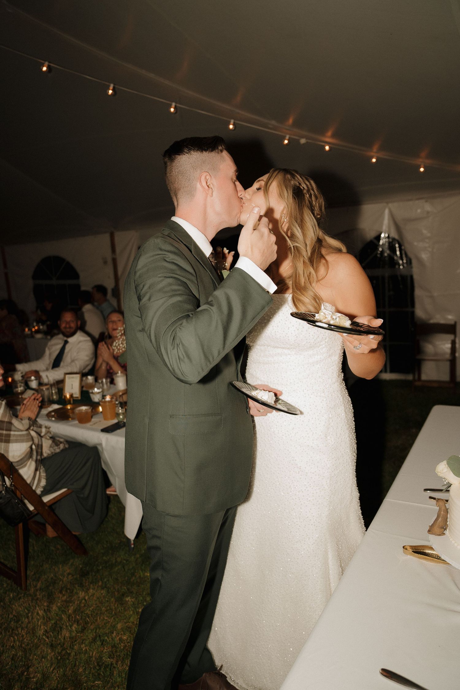 A couple shares a playful moment while tasting their wedding cake.