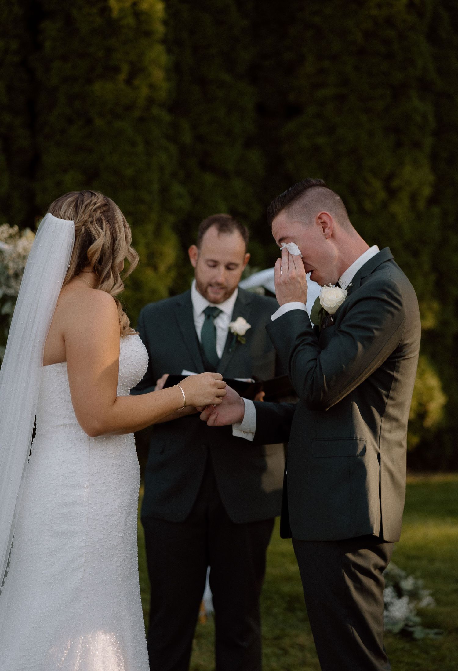 Emotional reactions during outdoor wedding ceremony with bridal party looking on.