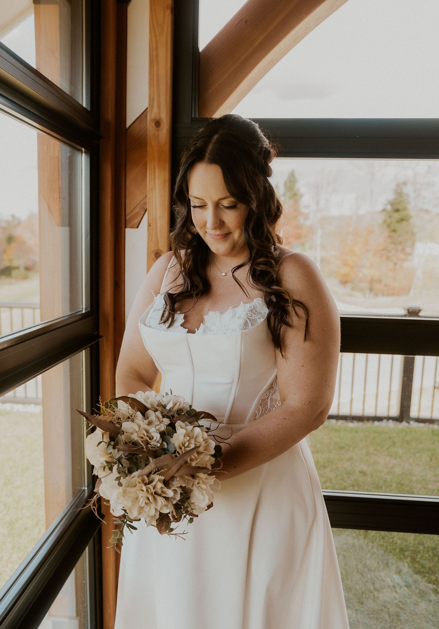 Elegant white wedding dress details shown in a sunlit room with natural window lighting.