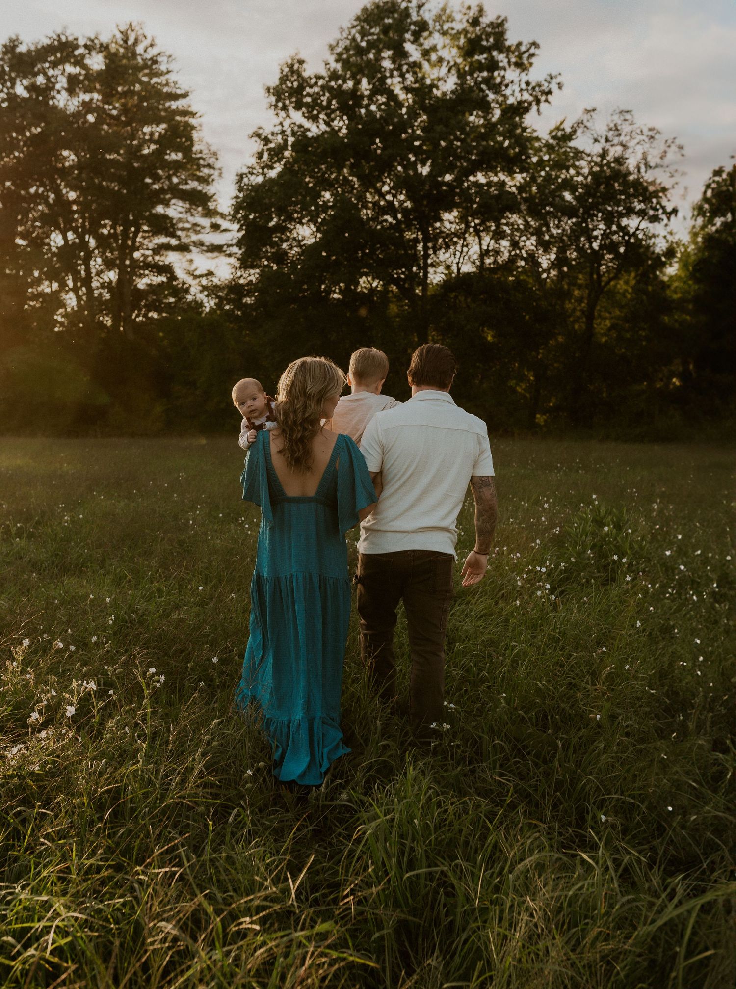Group walking through a golden field at sunset with trees in the background.