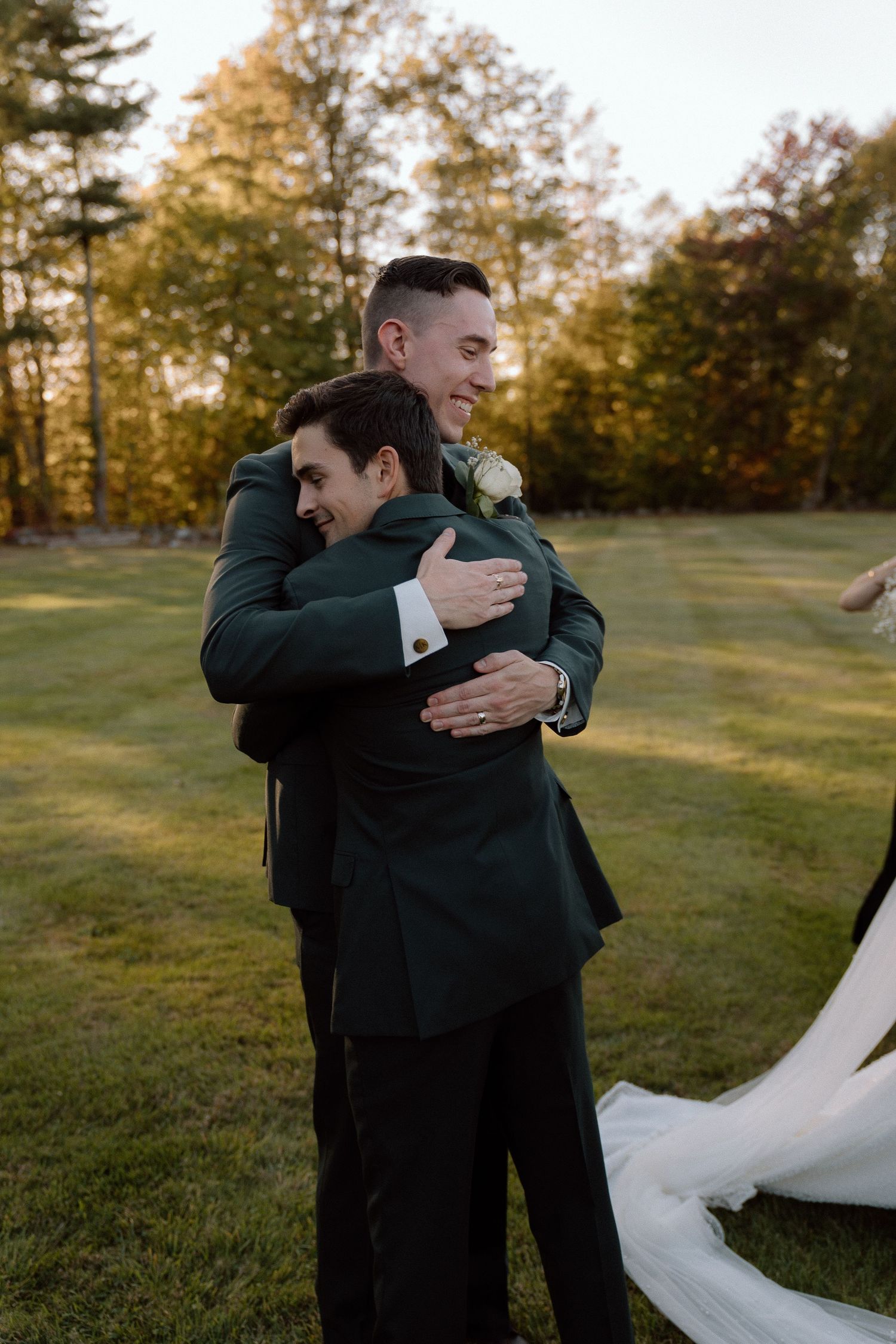 Heartfelt embraces shared during an outdoor wedding ceremony with autumn trees in the background.