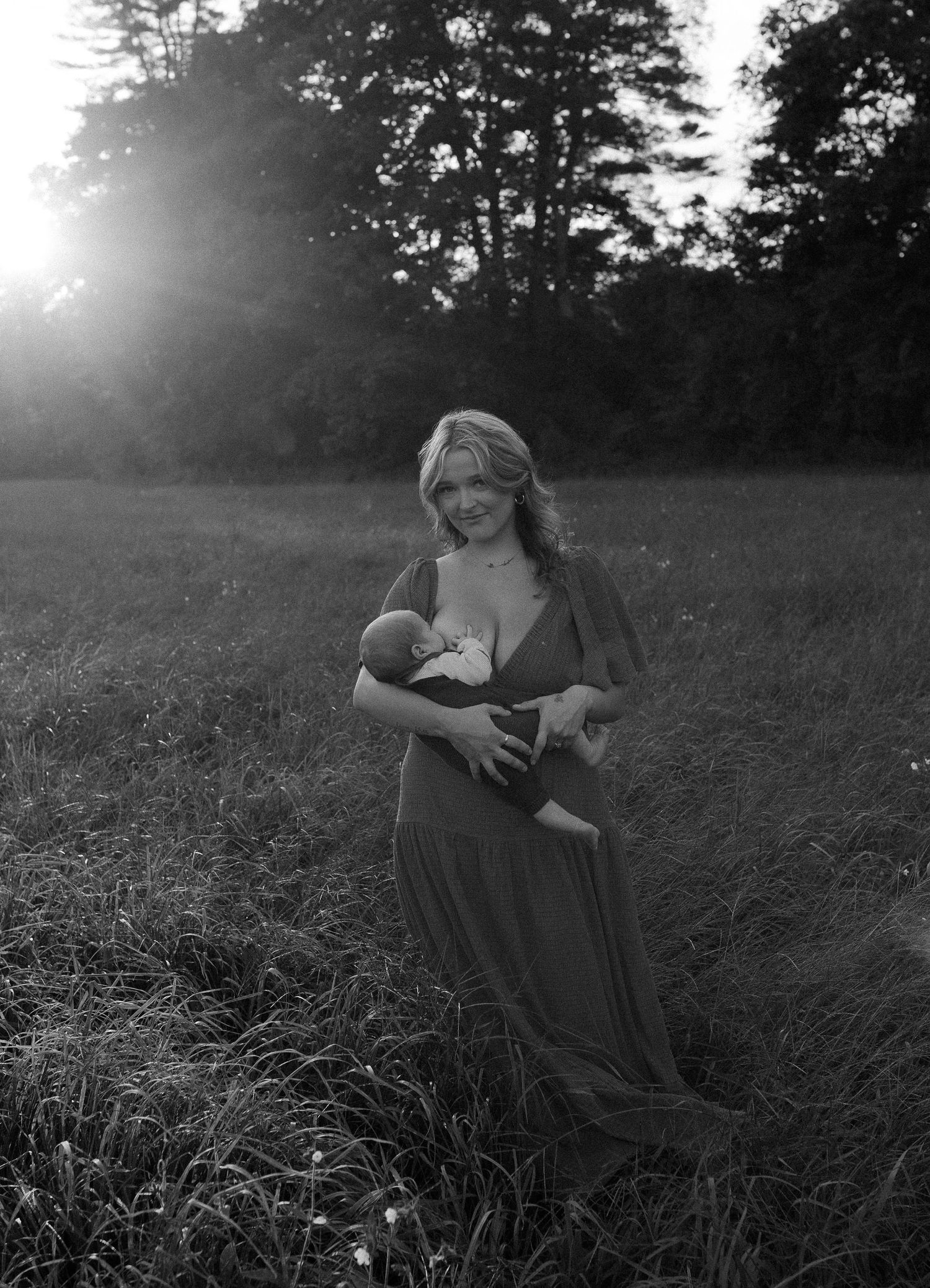 Black and white photo of people sitting in a field during sunset.