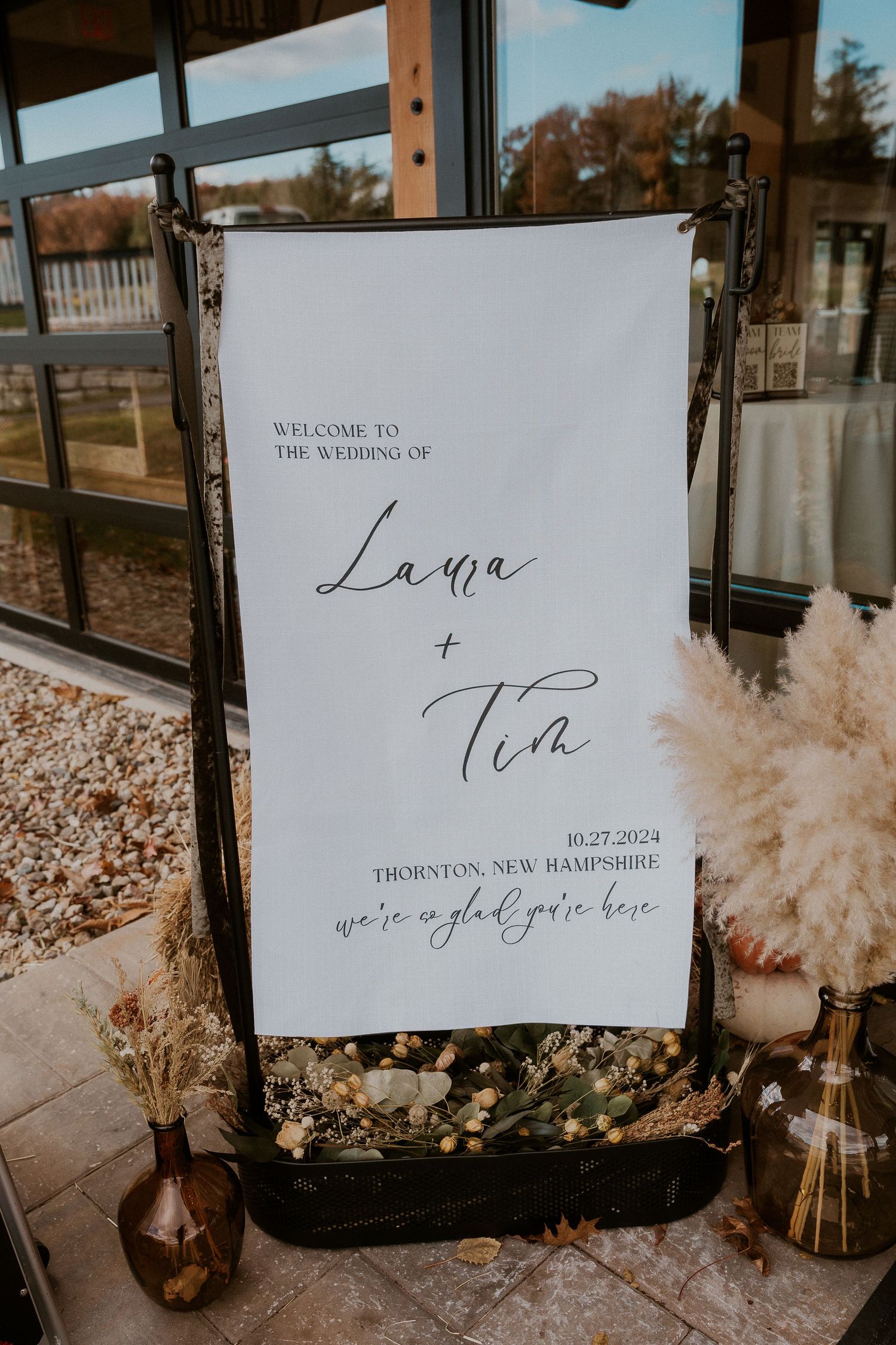Welcome signage with pampas grass decorations at wedding venue entrance.
