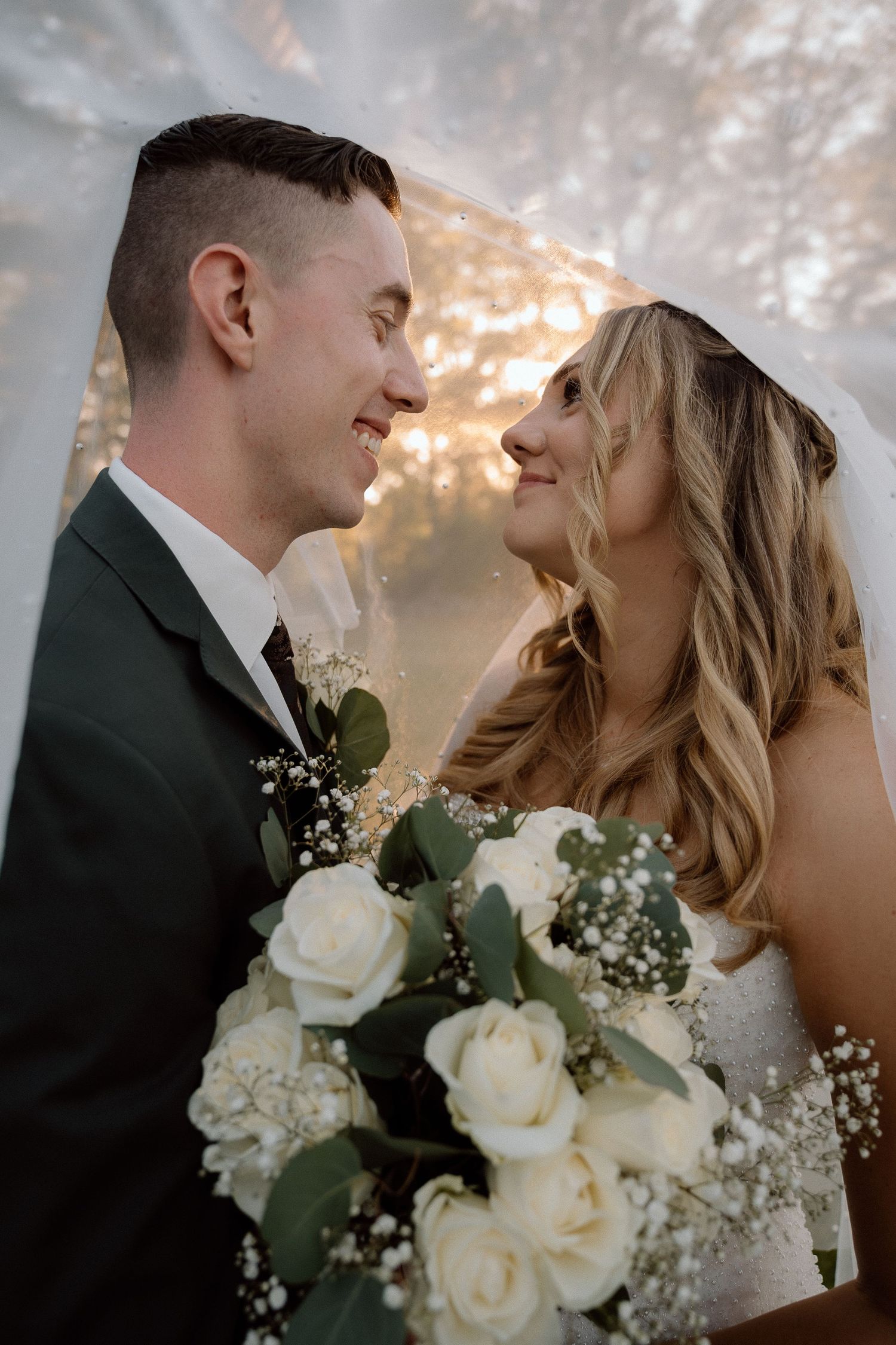 Intimate wedding portraits showing tender moments between newlyweds with white roses and baby's breath bouquet.