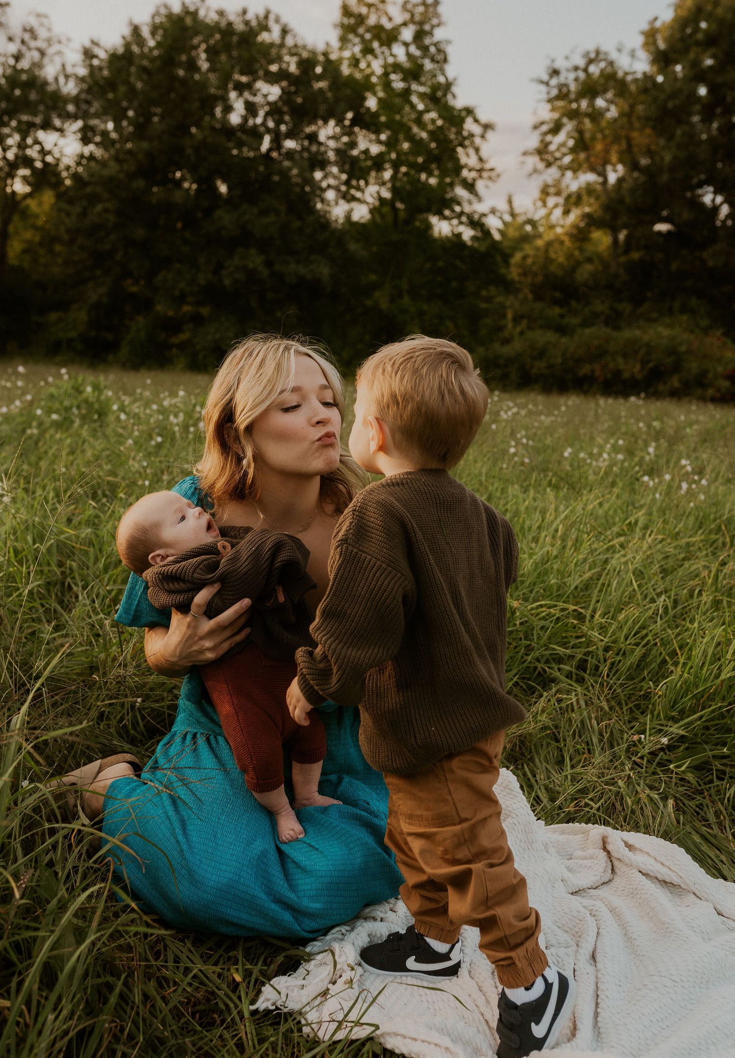 A tender family moment captured in a grassy field at sunset.