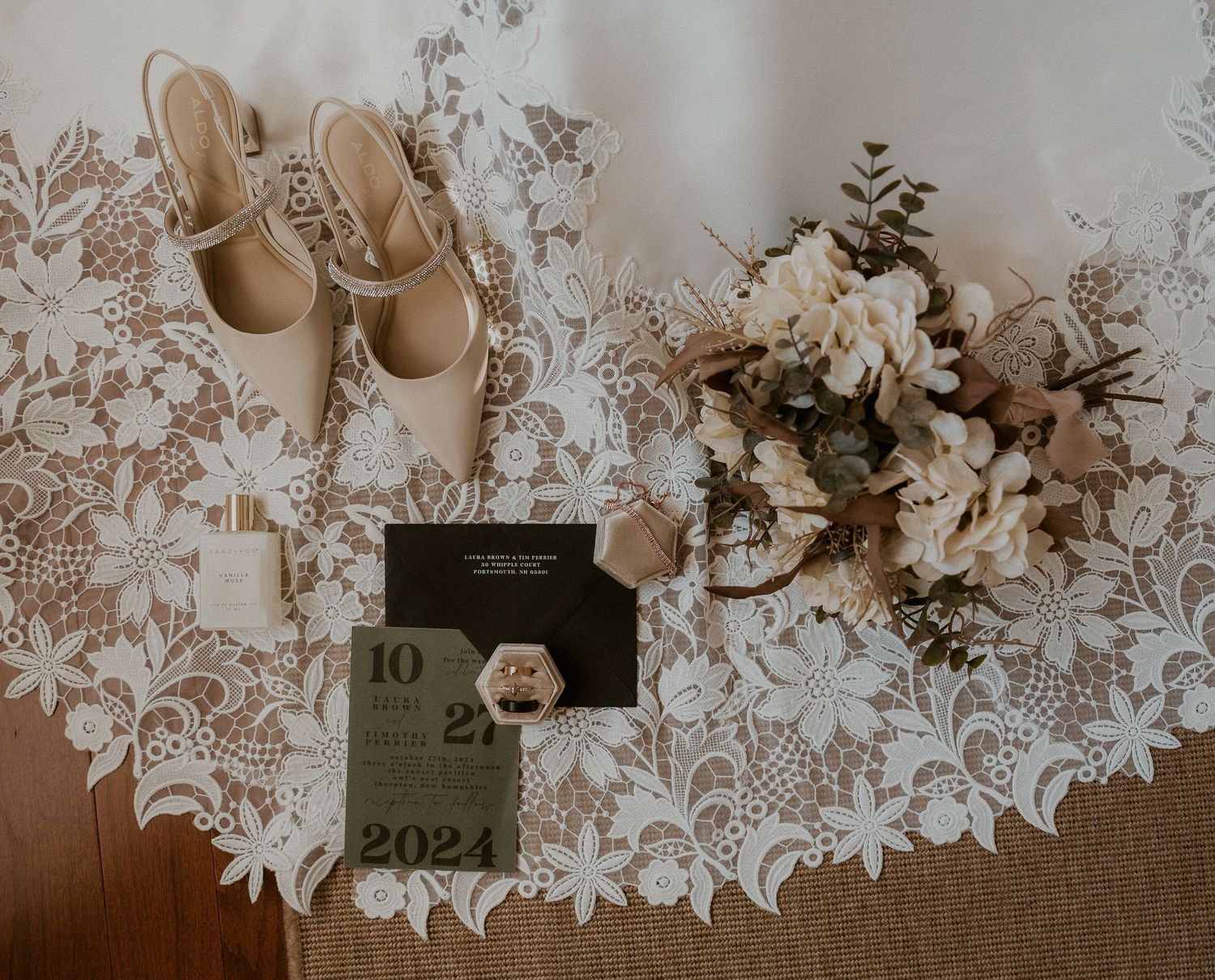 Wedding stationery and floral details arranged on textured burlap with lace overlay background.