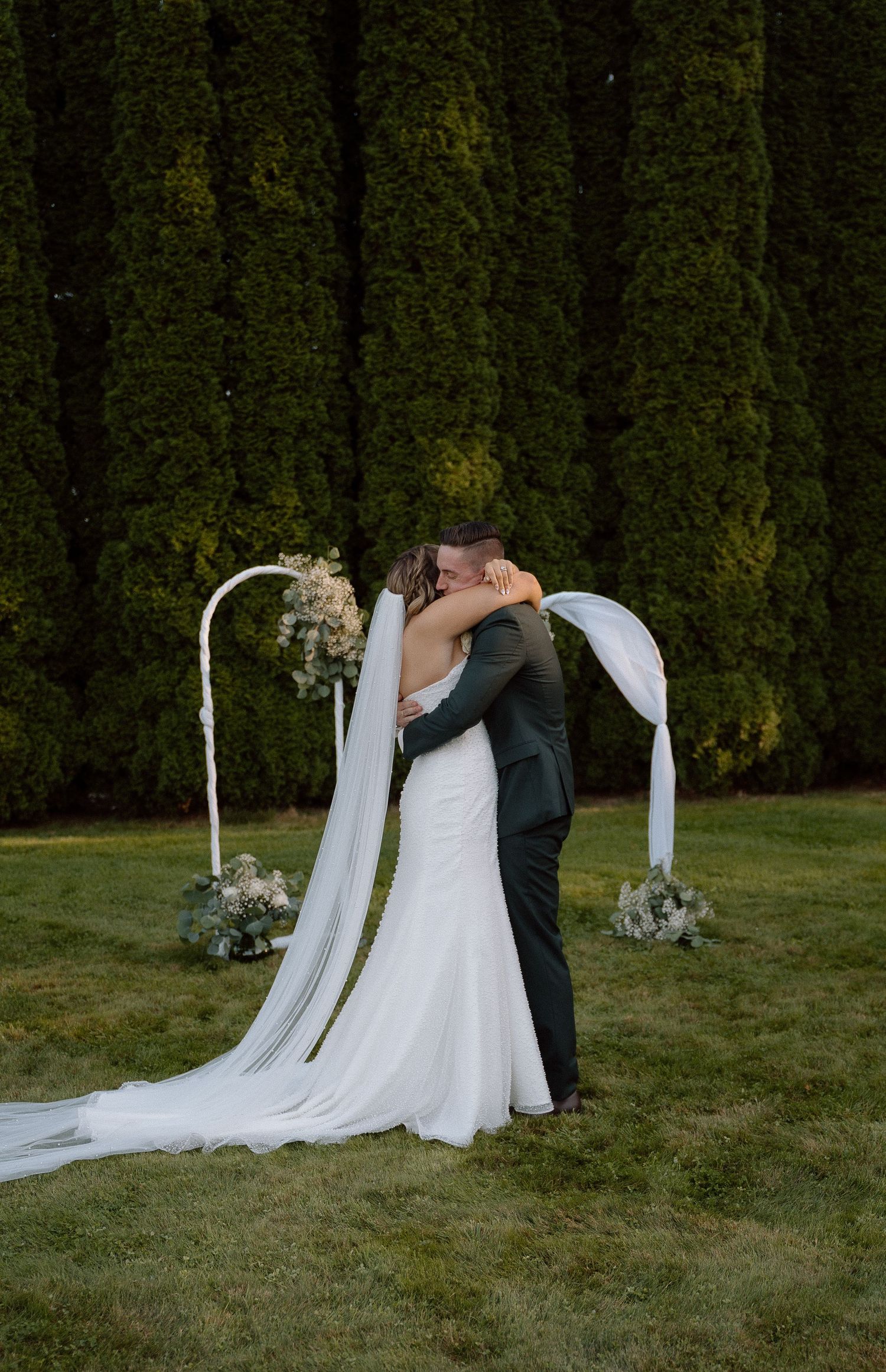 A romantic outdoor wedding moment captured against a backdrop of towering cypress trees.