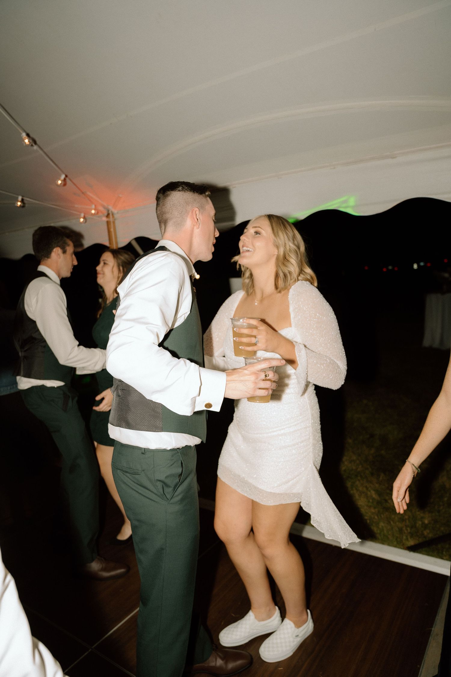 Wedding party members dancing enthusiastically at an evening reception.