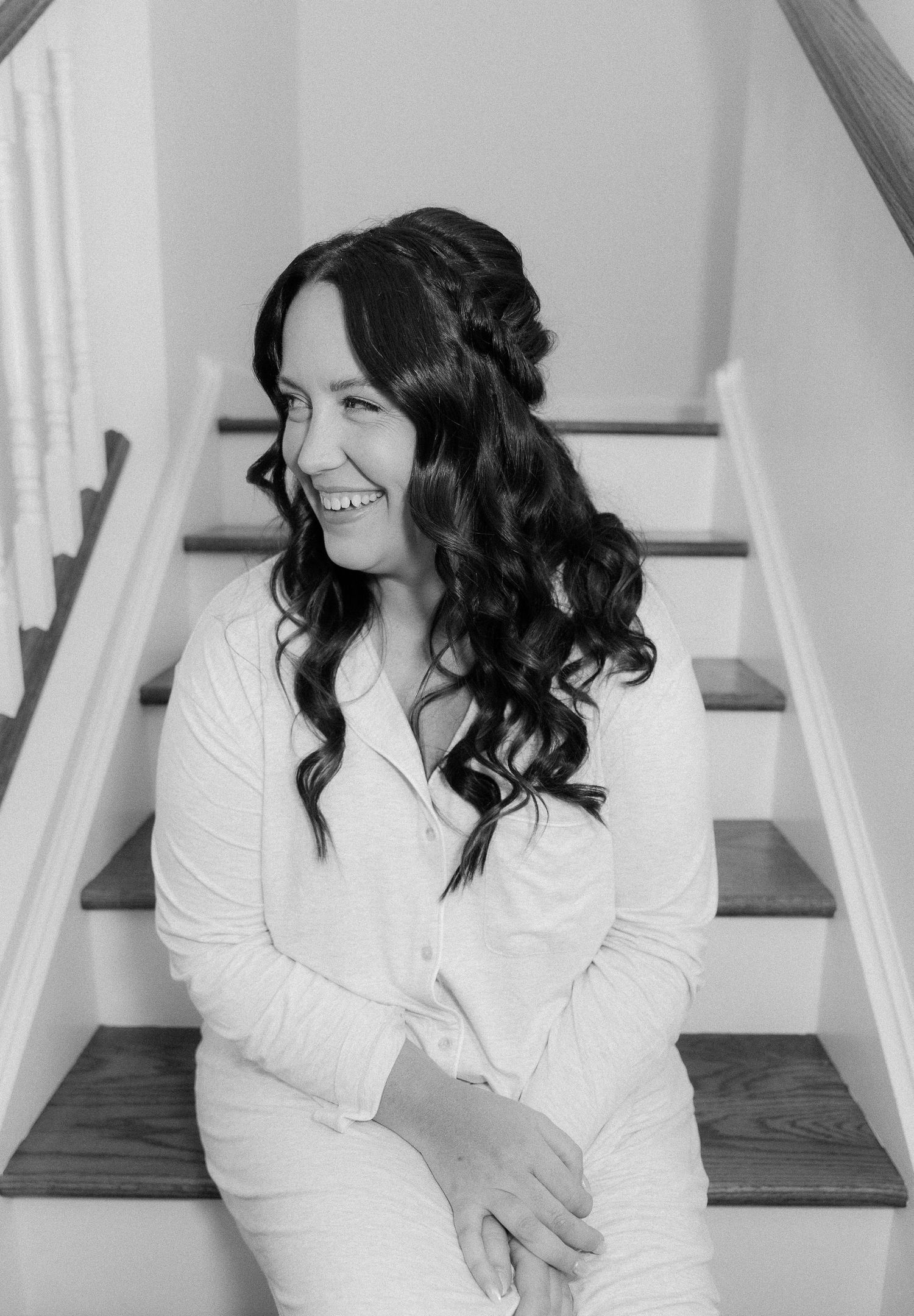 Black and white portrait on wooden stairs showing elegant bridal hairstyle with curls.