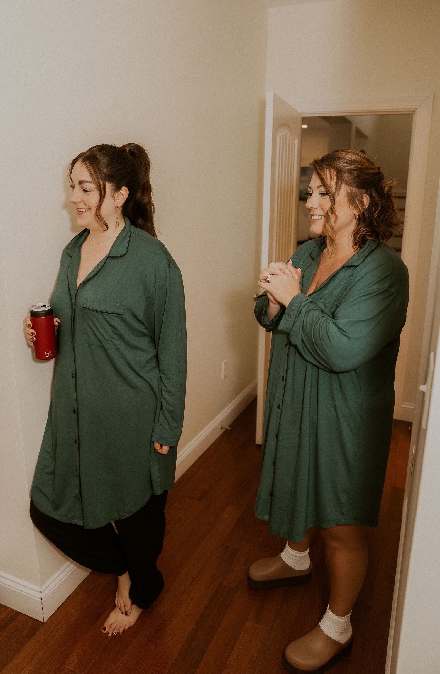 A person in a green button-up shirt and black shorts stands in a hallway taking multiple candid photos.
