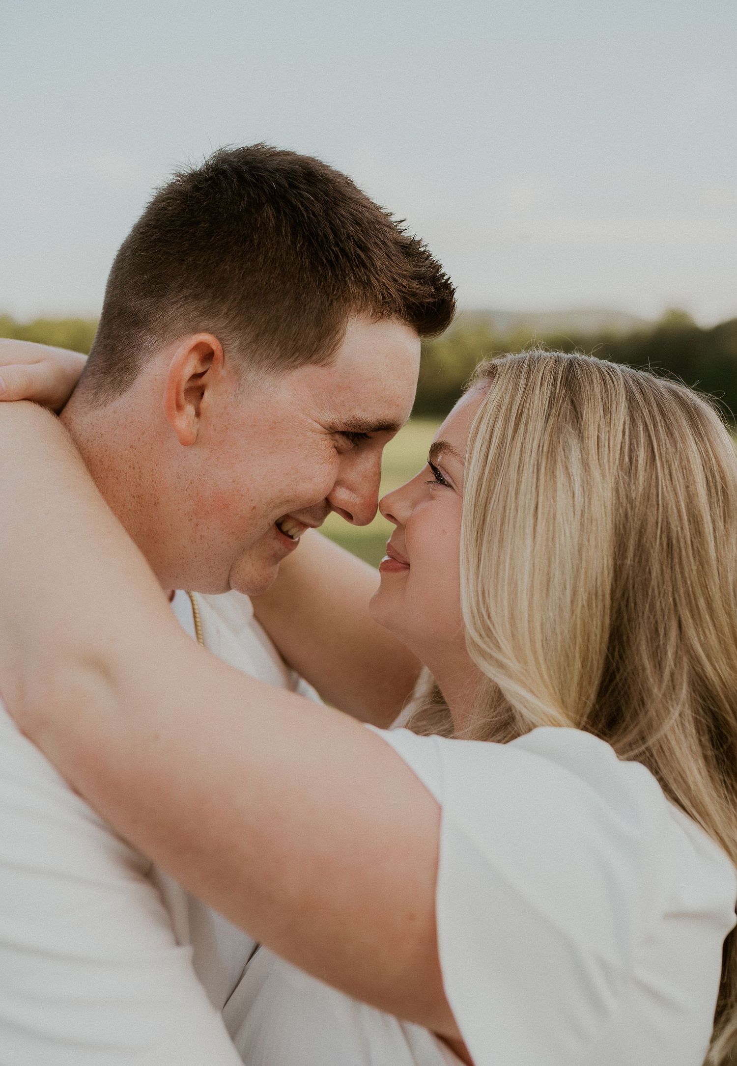 A romantic couple in white clothing share intimate moments in a series of close-up outdoor portraits.