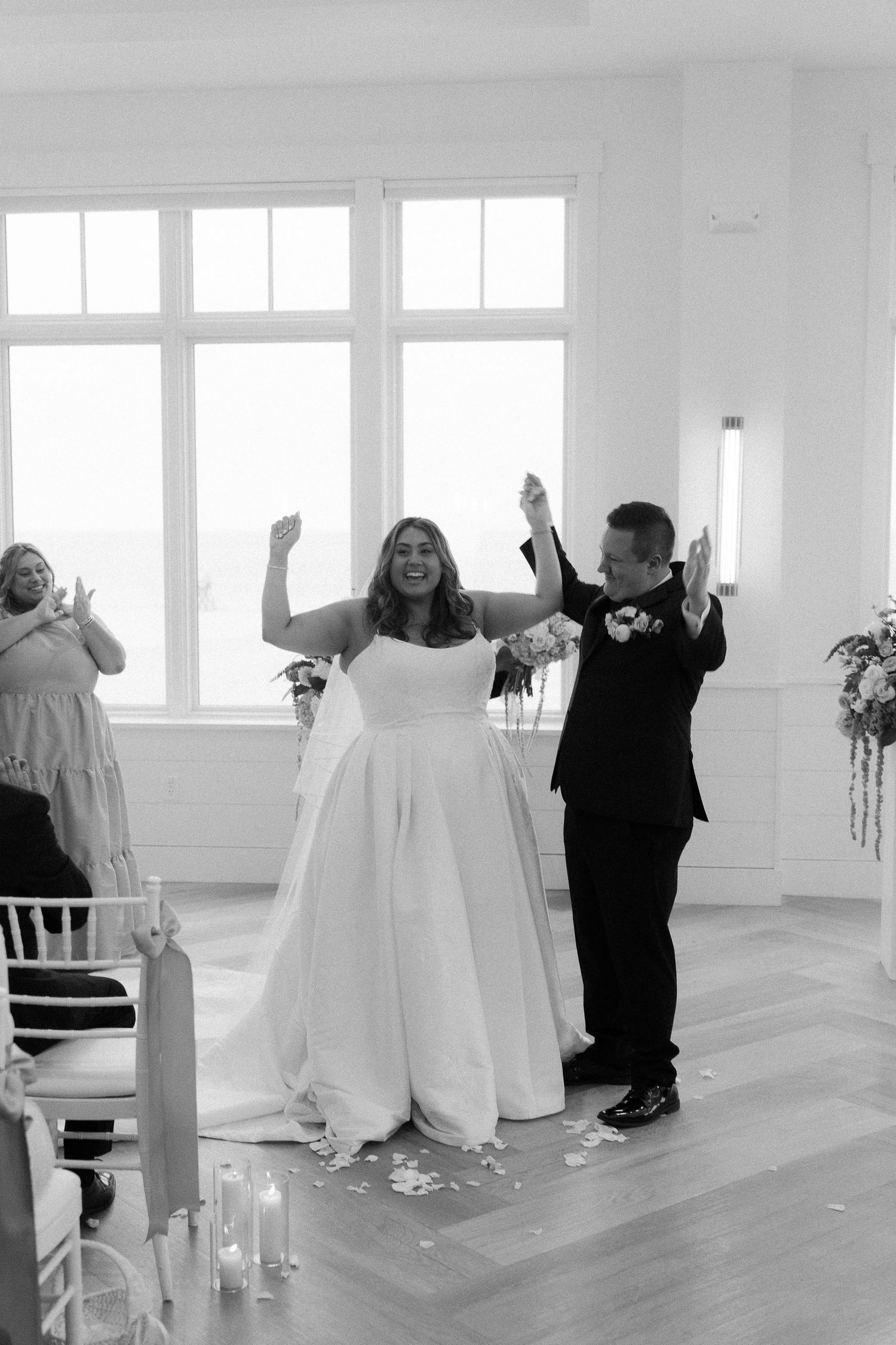 Bride and groom celebrate joyfully at the altar after exchanging vows in a bright white wedding venue.