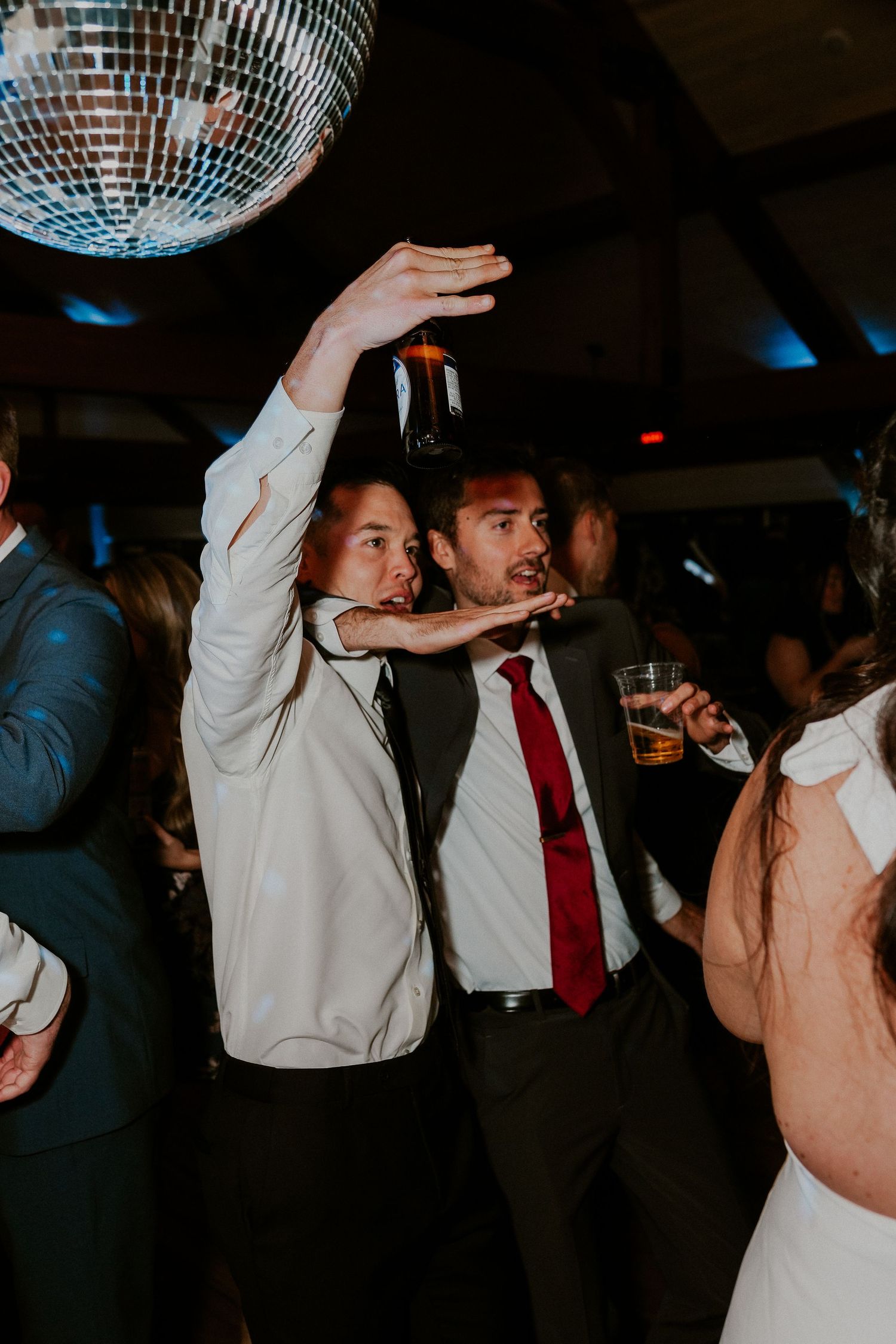 People dancing under a disco ball at a party with dramatic lighting and festive atmosphere.