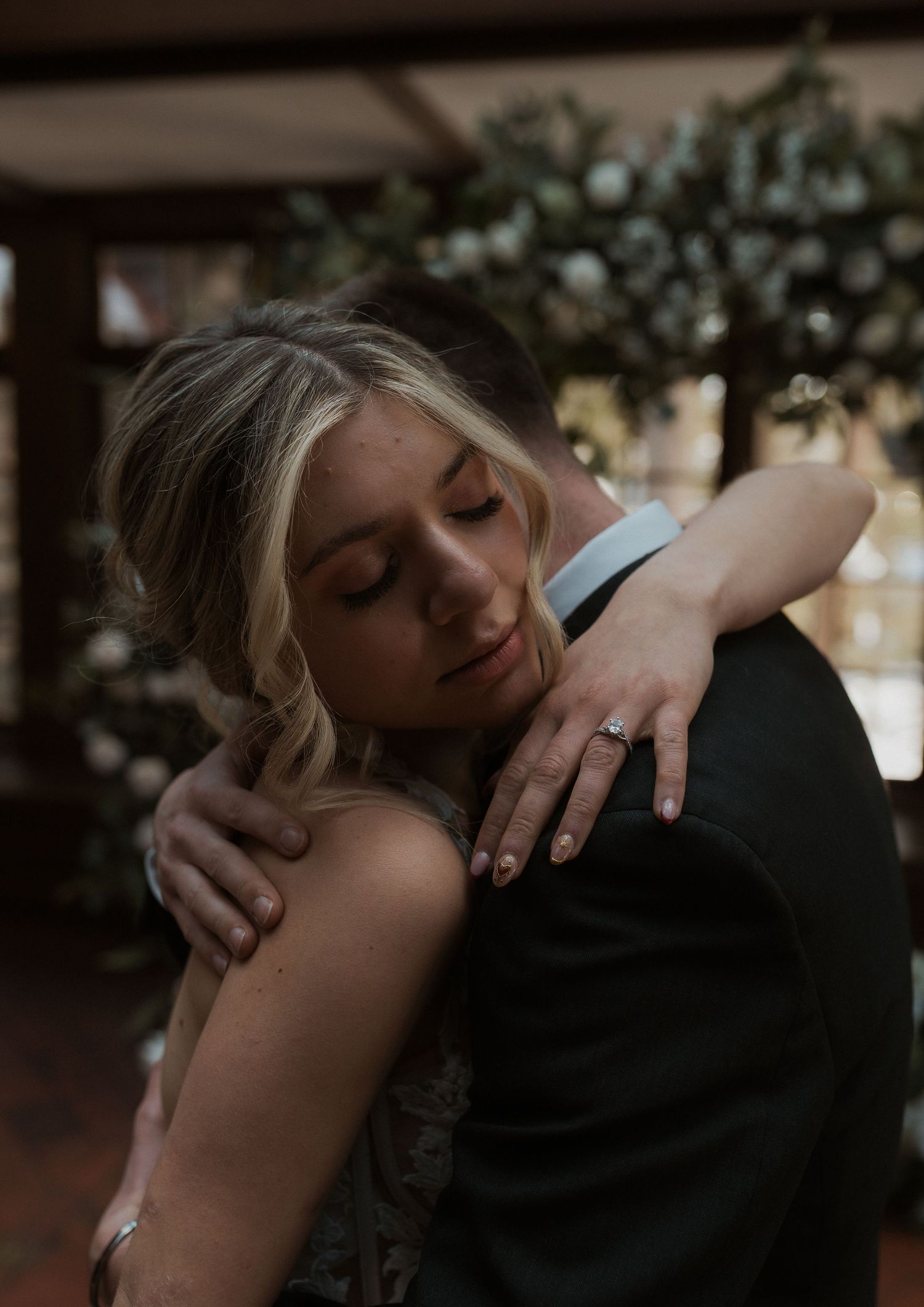 Intimate wedding moment showing couple embracing in elegant venue with floral decor.