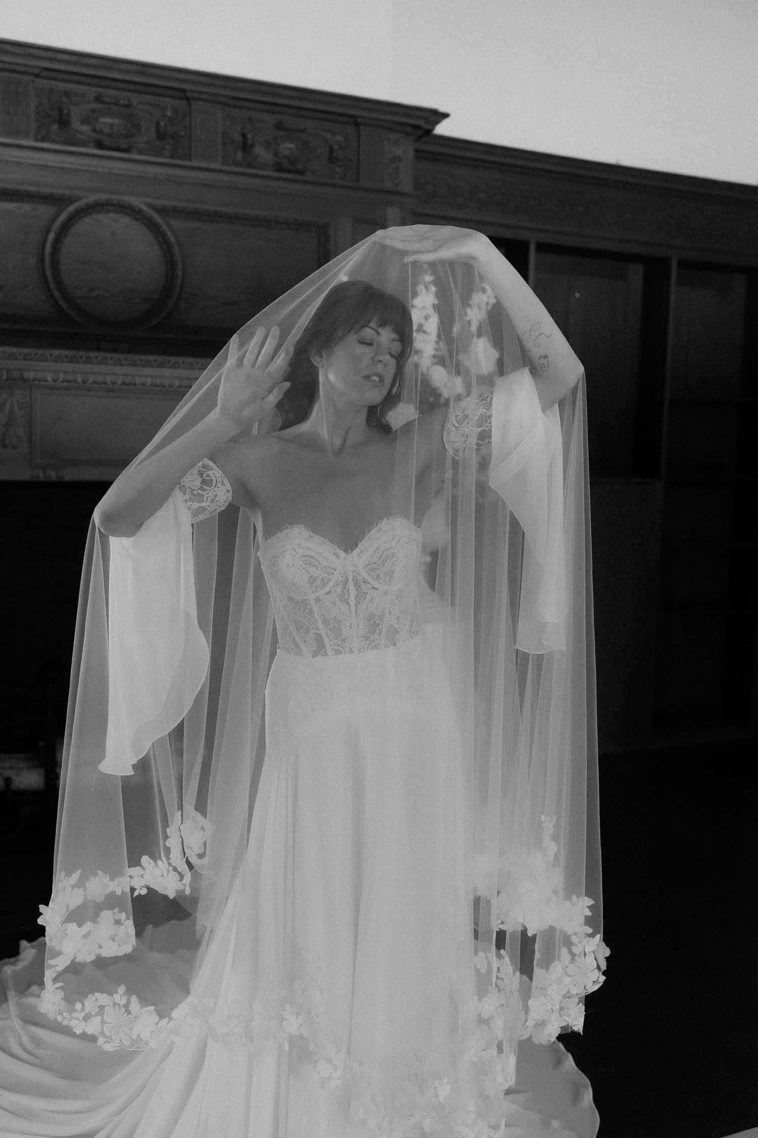 A dramatic black and white bridal portrait featuring a flowing lace veil and strapless gown.