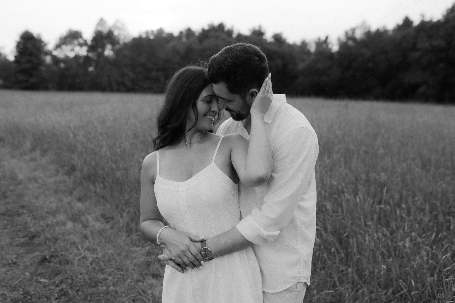 Romantic couple embracing in a field at sunset during a photo session.
