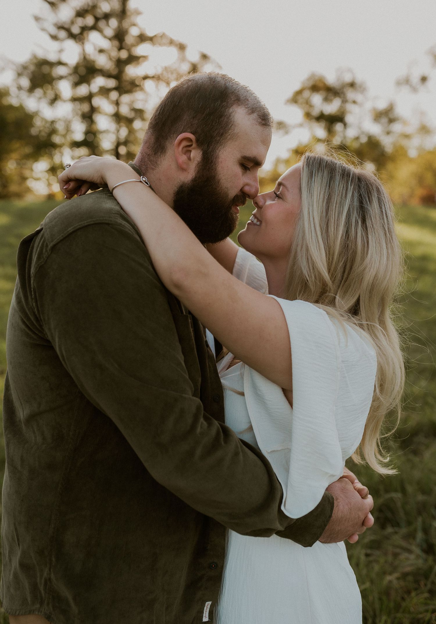 Romantic sunset engagement photoshoot showing tender moments between a couple in a natural outdoor setting.