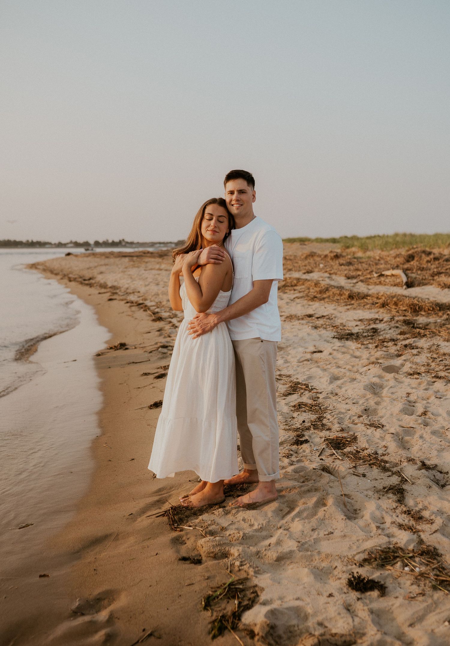Romantic beach portraits of a couple in white clothing during golden hour.