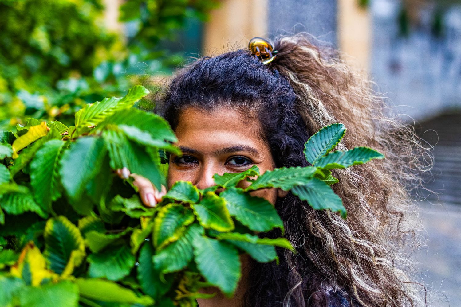 Genuine female portrait in the city under natural light playing with nature by Gerard Su Photography.