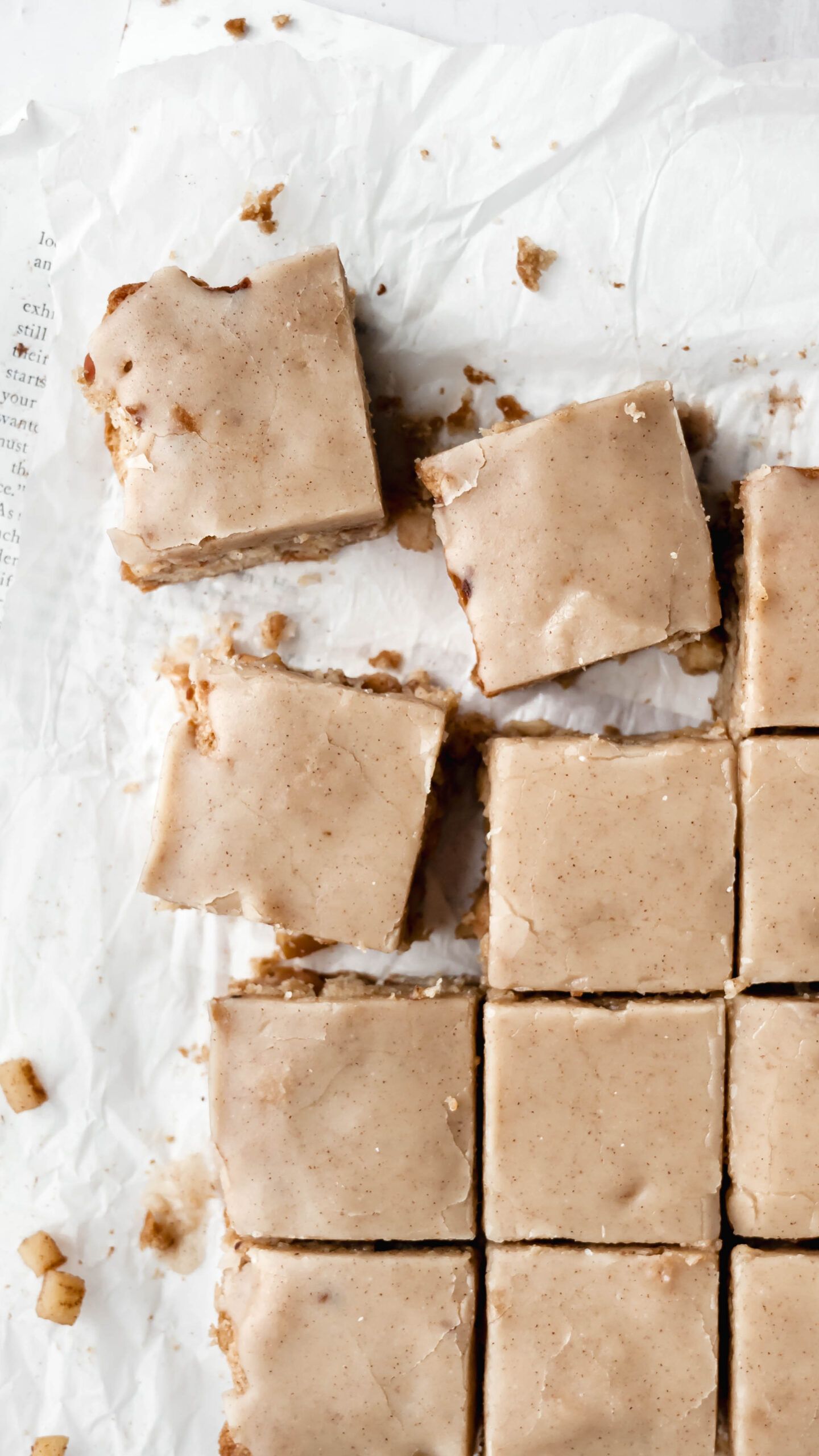 Homemade caramel fudge squares arranged on white parchment paper with a soft beige color and crumbly texture.