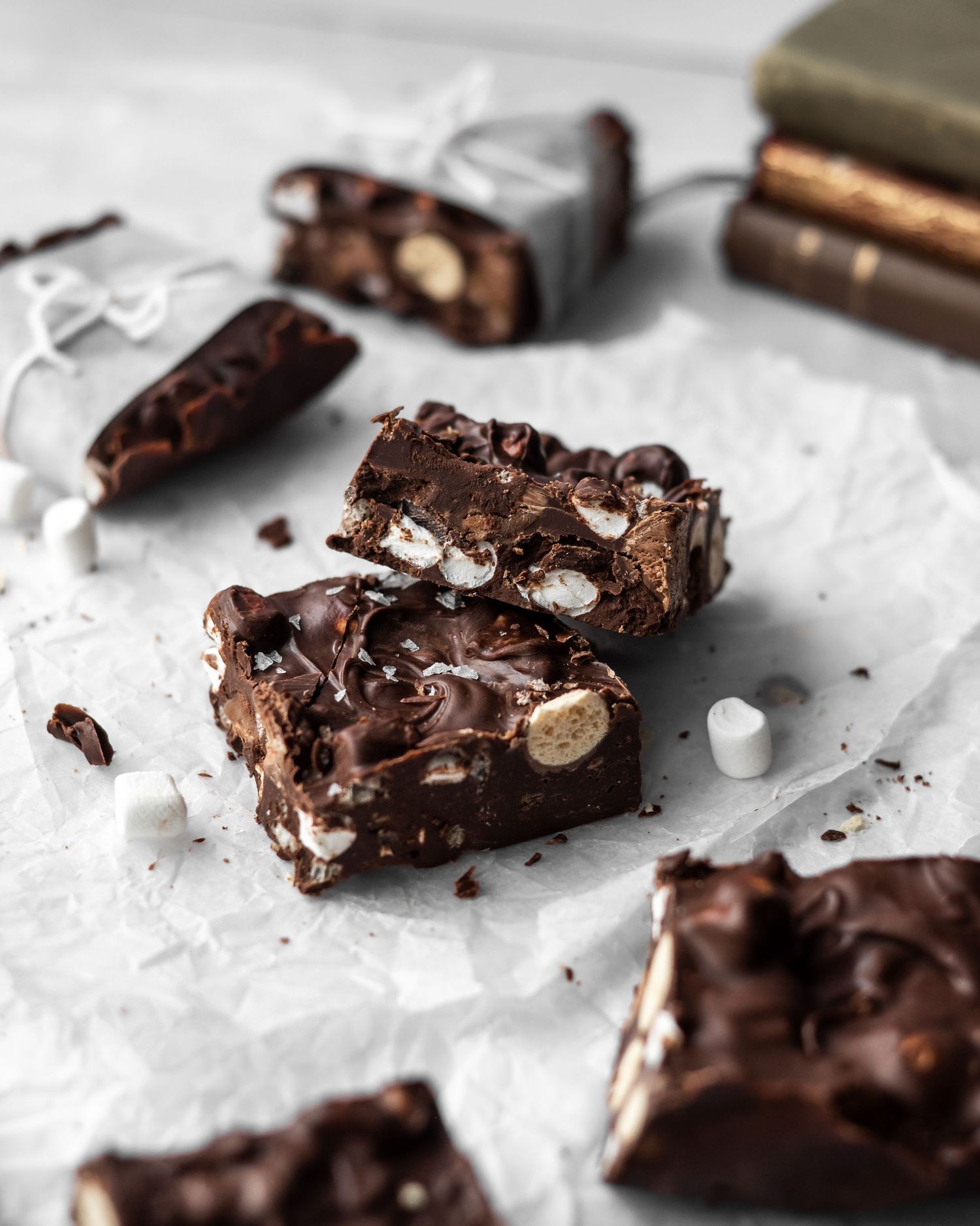 Homemade rocky road candy with chocolate, marshmallows and nuts broken into pieces on white parchment paper.