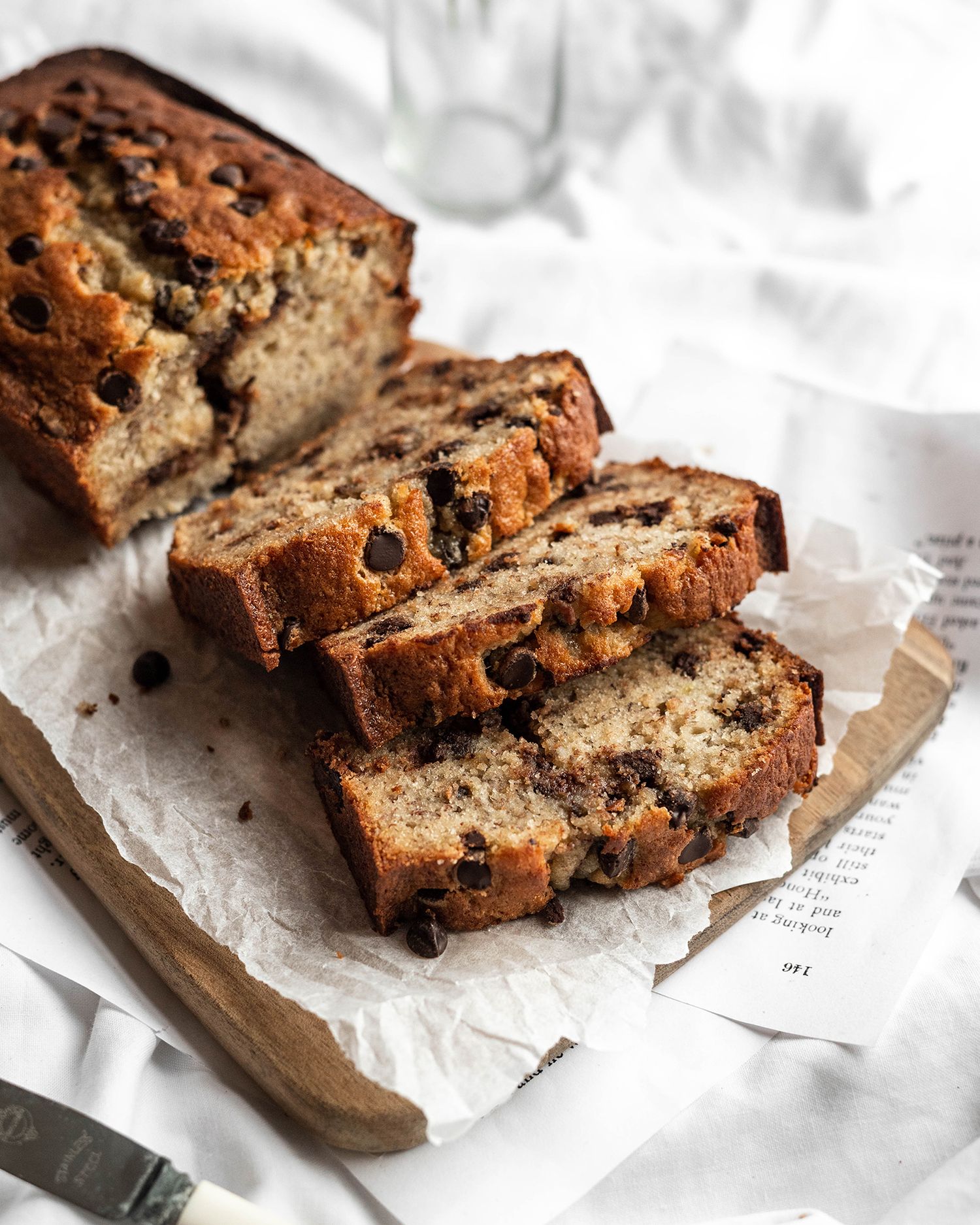 Sliced chocolate chip banana bread loaf displayed on parchment paper showing rich texture and melty chocolate chips.
