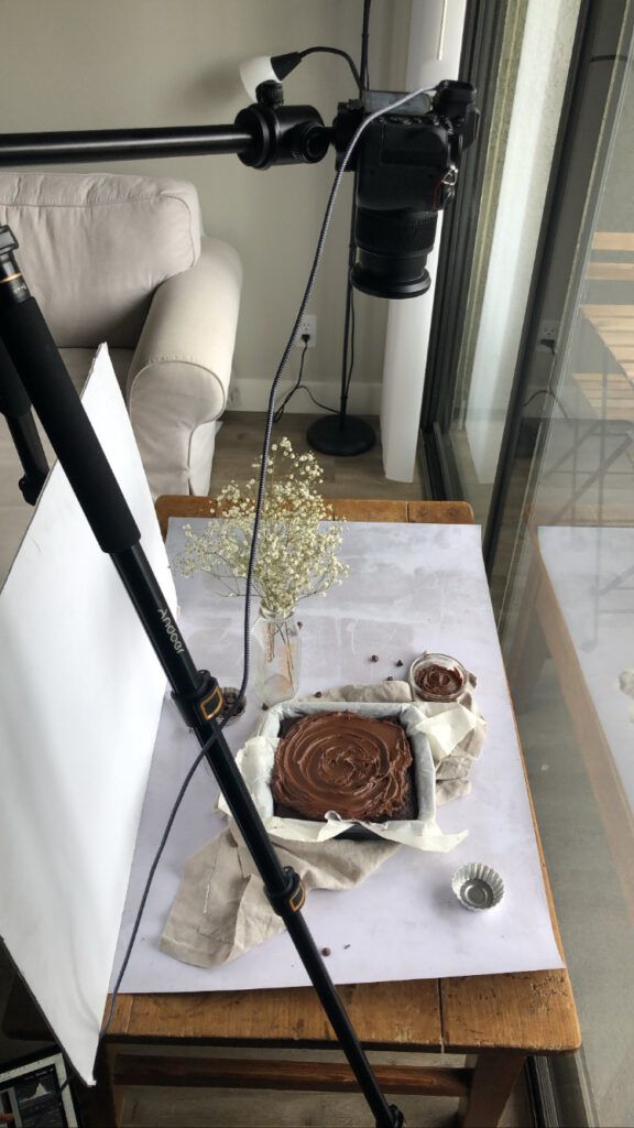 Photography setup with lighting equipment and chocolate dessert arranged on white surface for food photography shoot.