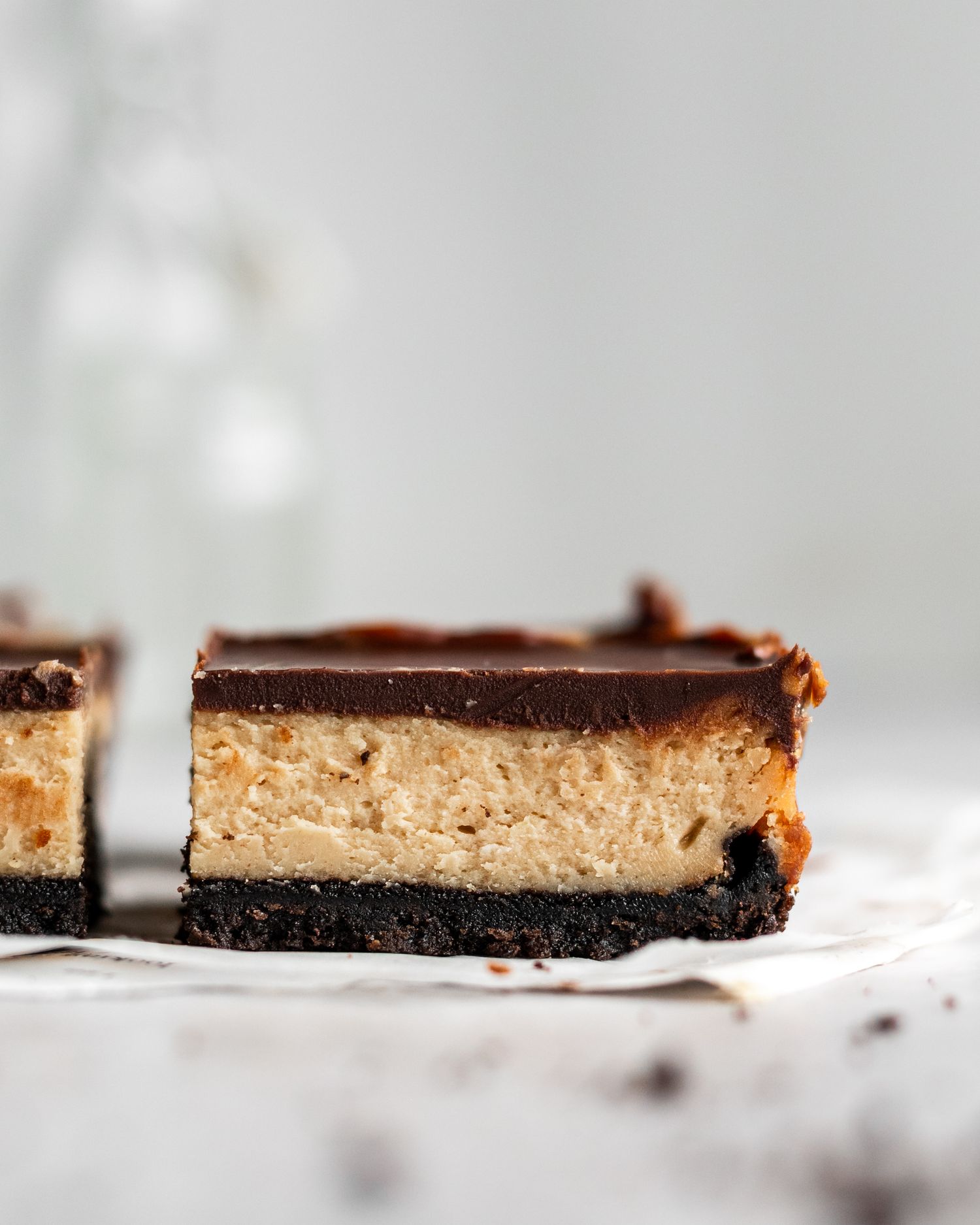Close up of chocolate peanut butter cheesecake bar with chocolate ganache topping and Oreo cookie crust.