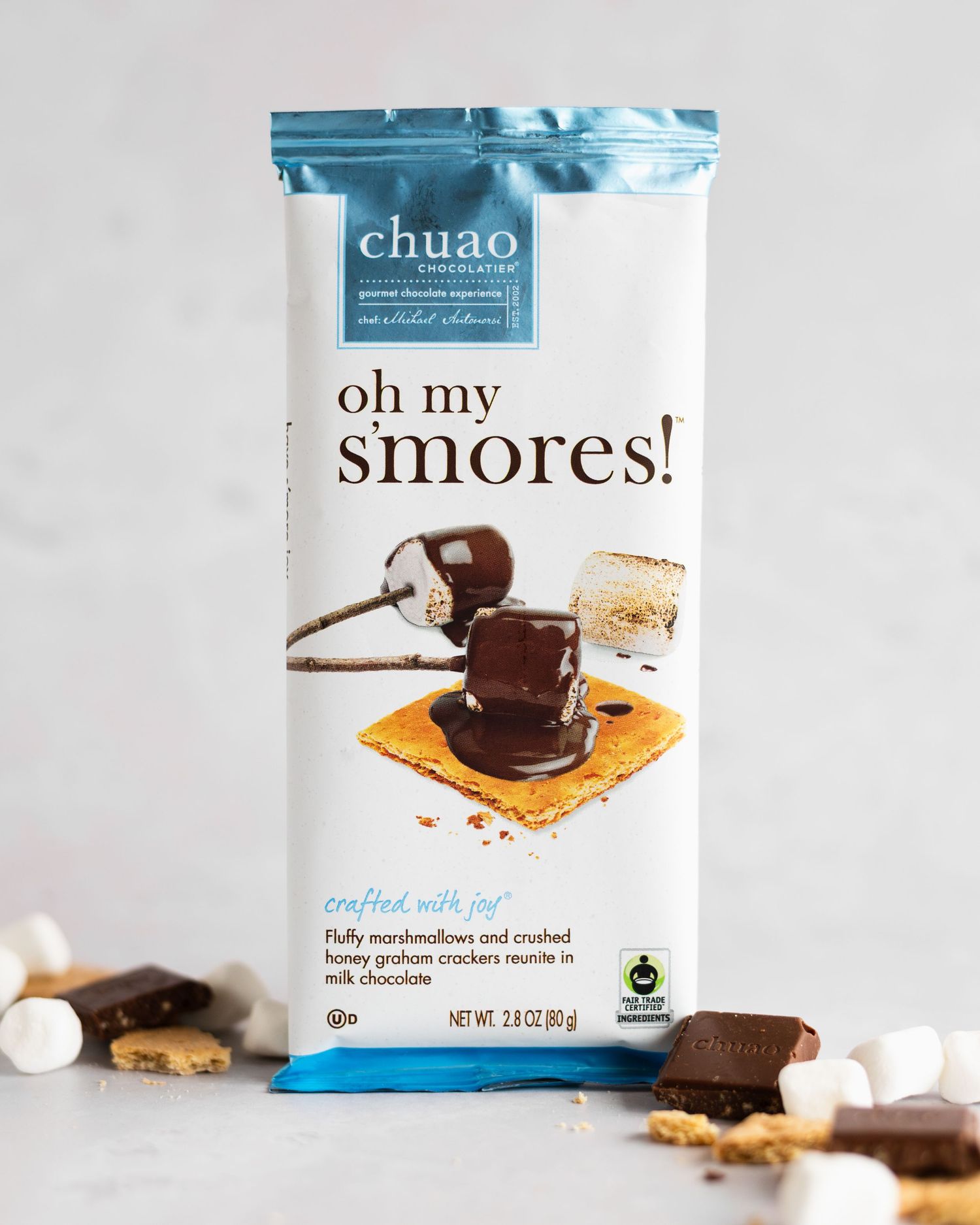 White bag of 'oh my smores' chocolate snacks shown from multiple angles on a light gray background with scattered pieces.