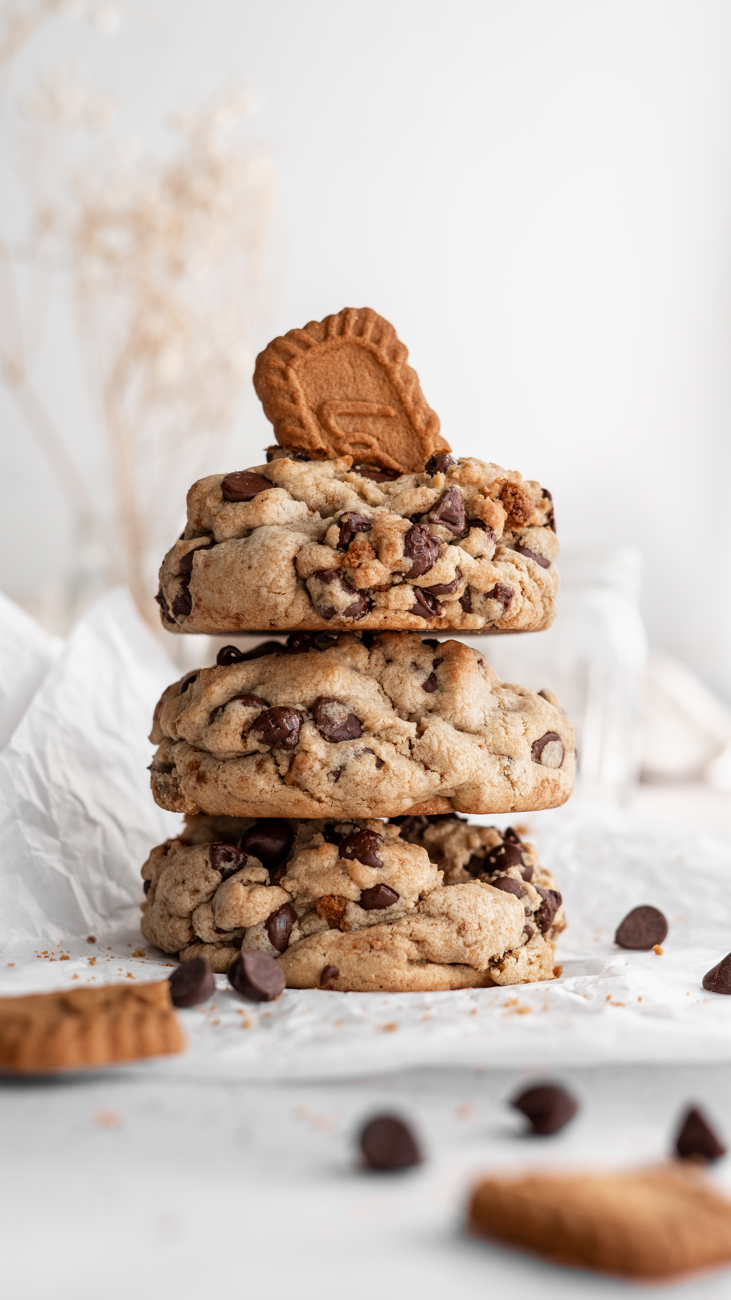 Several stacked chocolate chip cookies with chunks of peanut butter cups on a white surface.