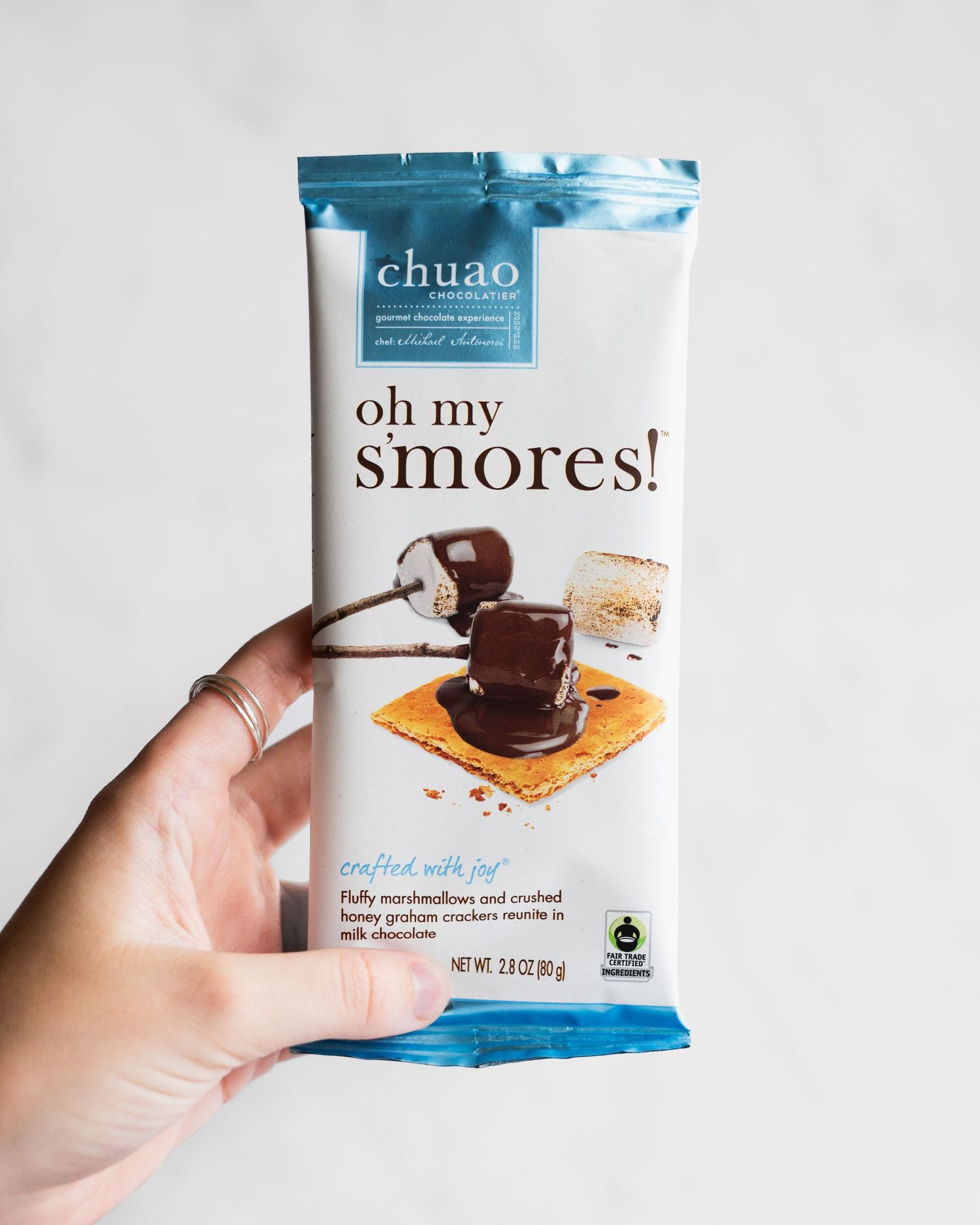 A progression of someone opening a packaged chocolate s'mores snack from 'Oh My Smores!' brand.
