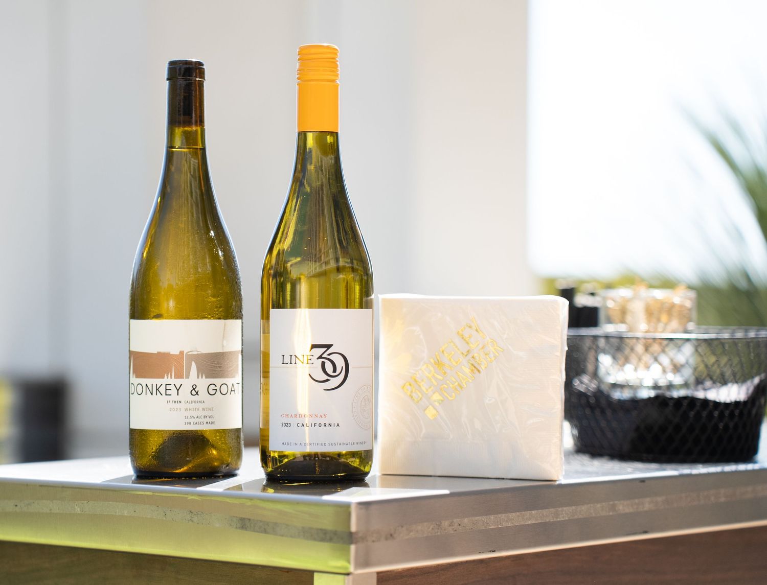Wine bottles and glasses displayed on a white surface in natural lighting.