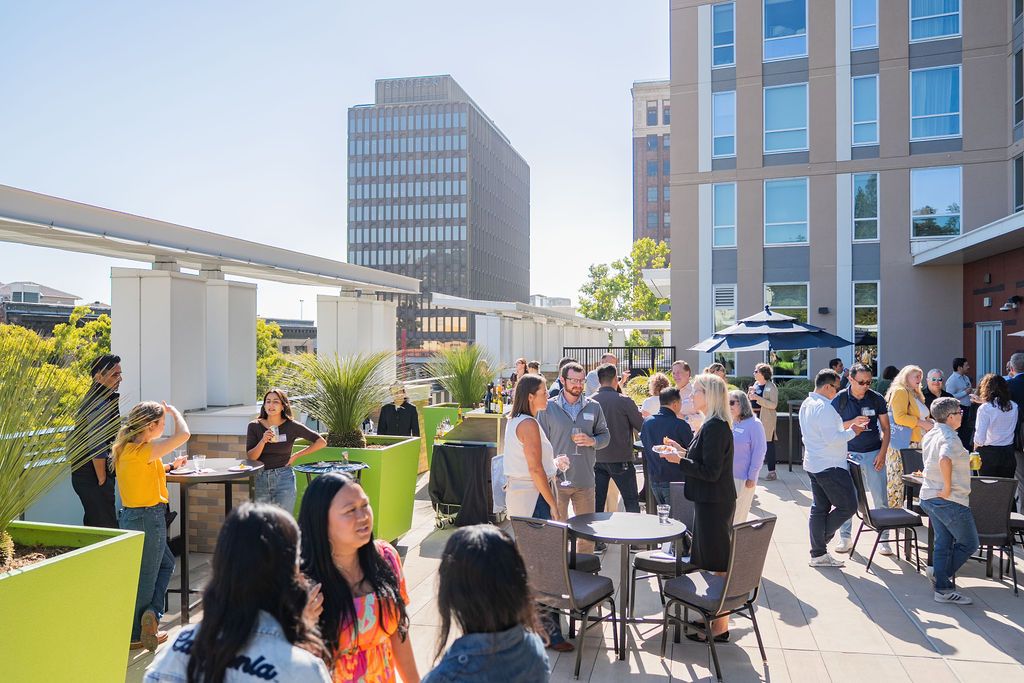 Guests networking and mingling on an outdoor terrace at a Berkeley business event with city views and natural light.