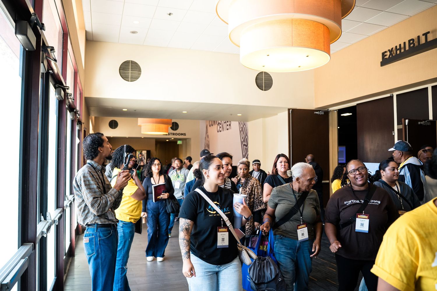 A busy crowd of people gathered in a hallway at what appears to be a convention or conference venue.