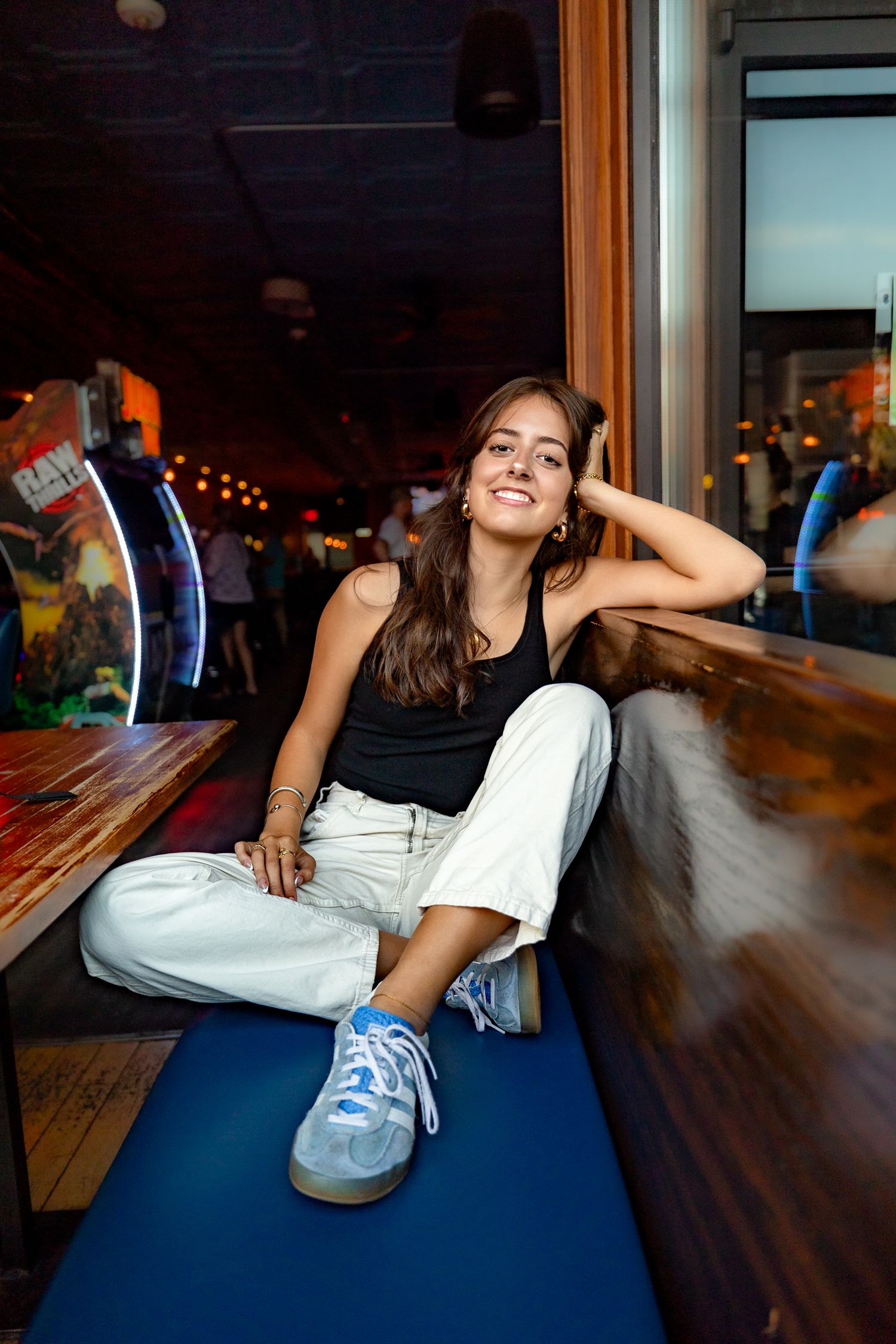 Person in casual attire posing on blue mat in dimly lit indoor setting.