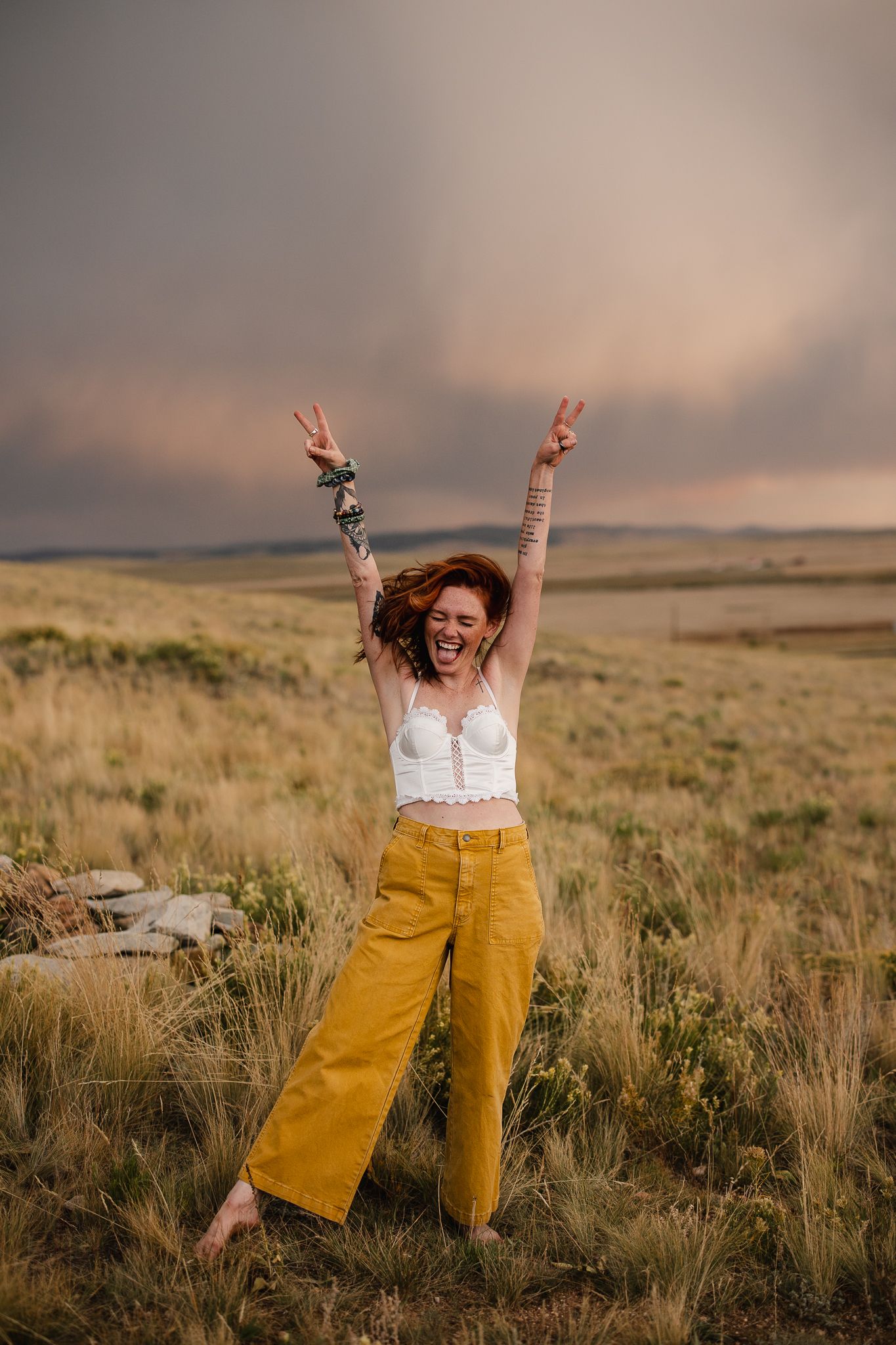 Joyful outdoor scene in yellow pants and white top against prairie landscape.