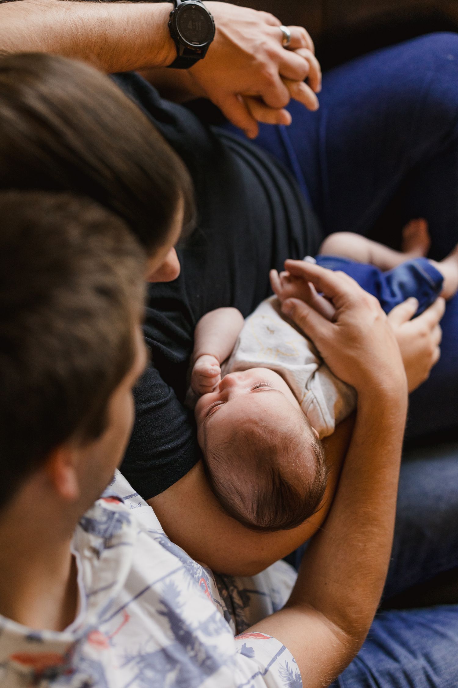 Family members gathered closely, lovingly cradling a newborn baby in their arms.