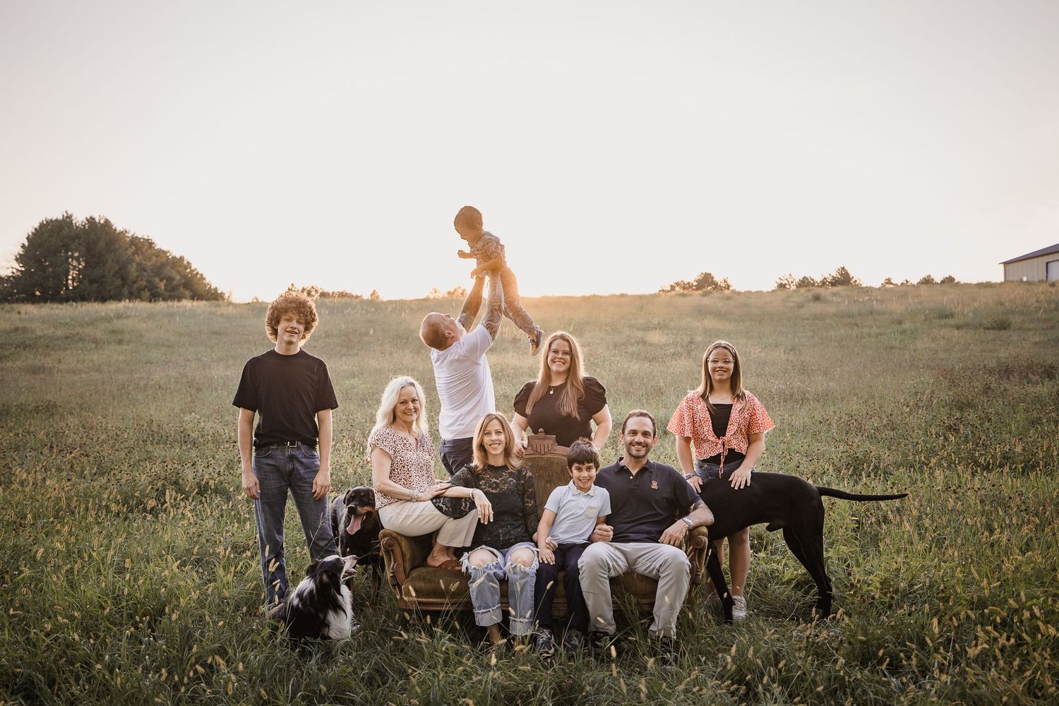 A group of people sitting together on benches in an open field during golden hour.