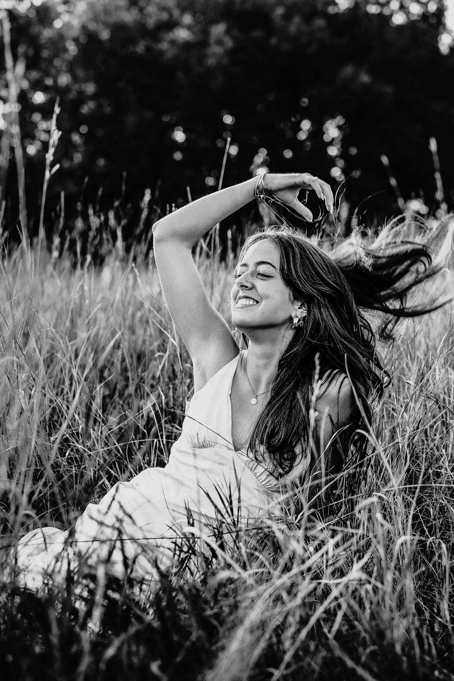 Person lying in tall grass during dramatic black and white photoshoot.