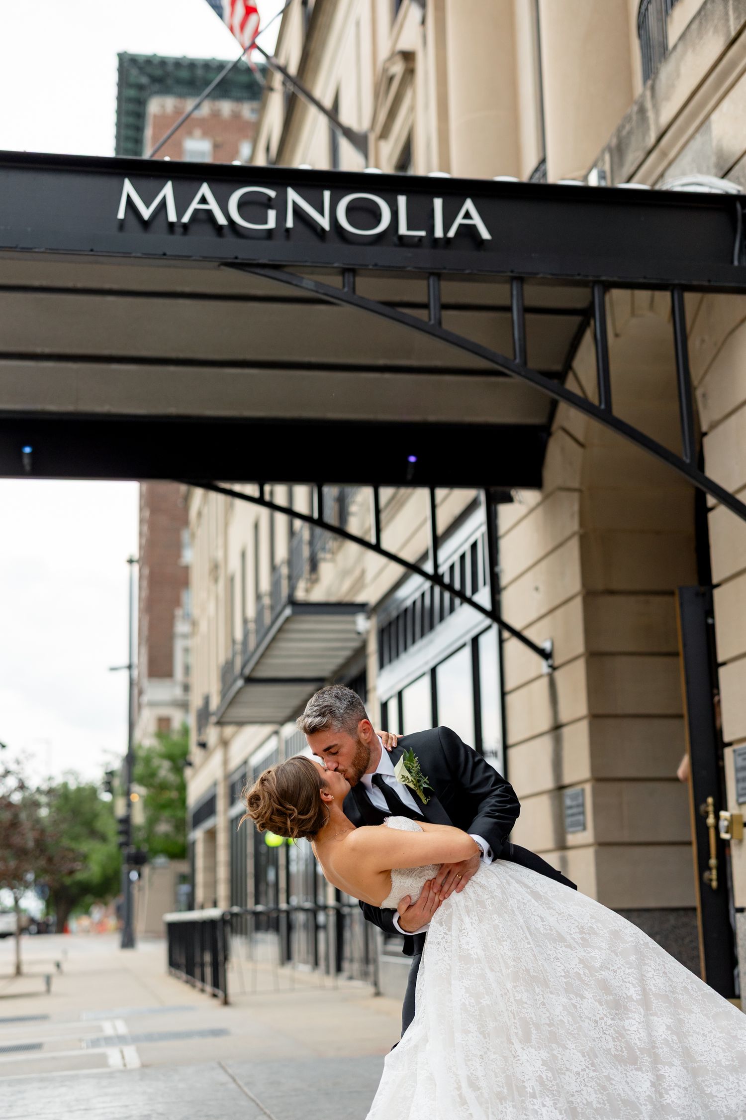 Bride and groom share a dip kiss under the Magnolia hotel awning on their wedding day.