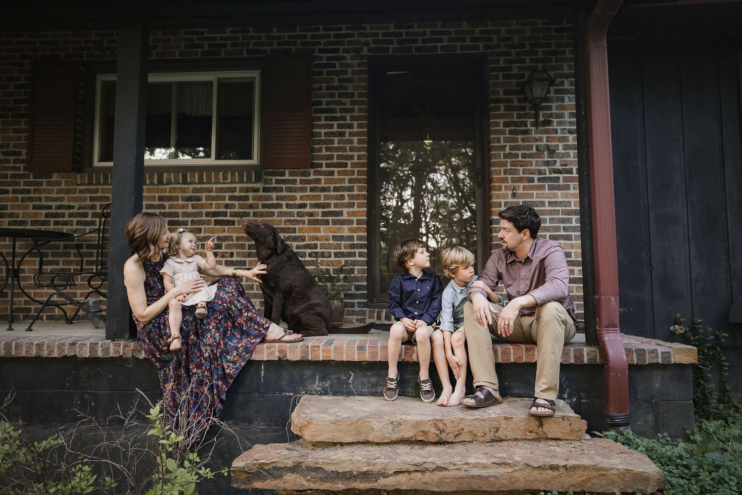 Family lifestyle scene captured on a rustic brick porch.