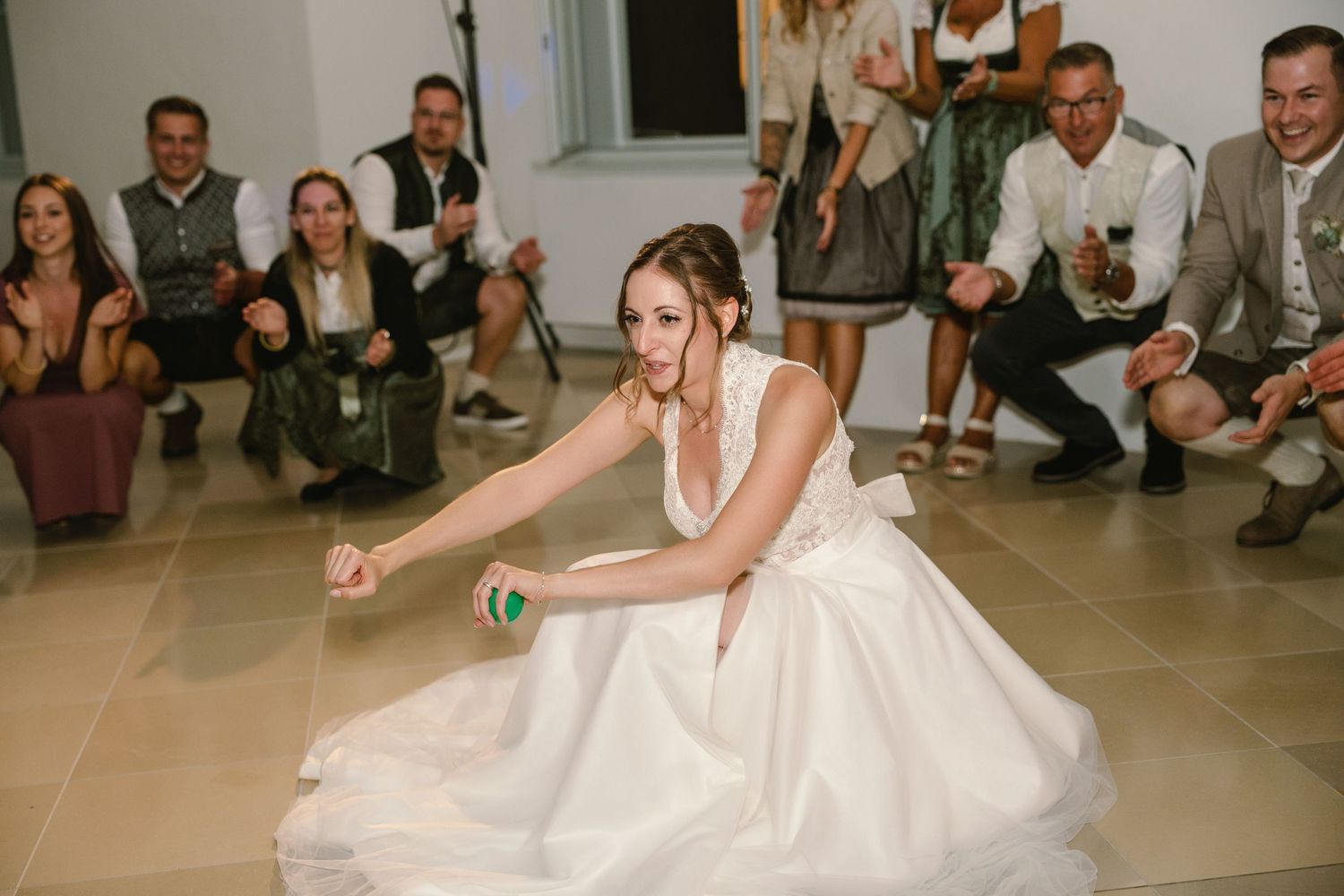 Bride in flowing white gown dances energetically during wedding reception.