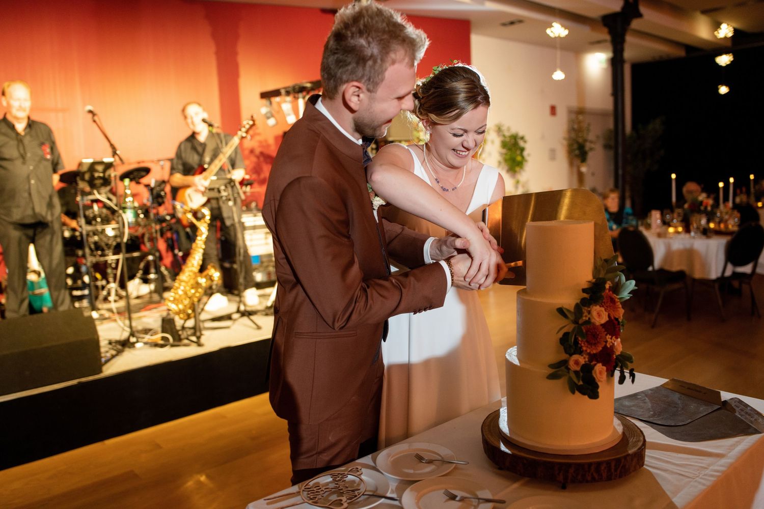 Wedding reception venue with orange ambient lighting and decorated tables.