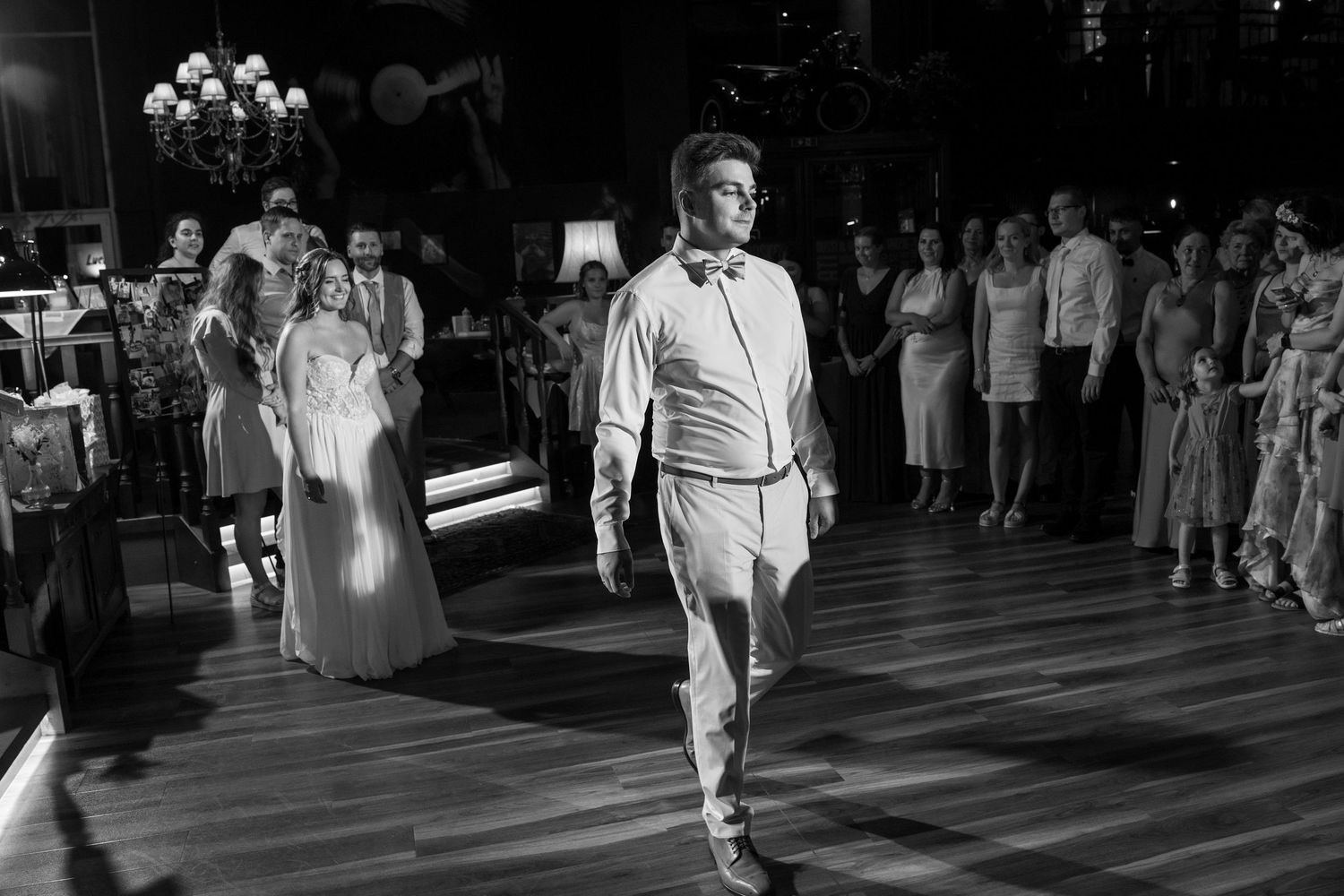 Wedding guests dancing in formal attire on a dimly lit dance floor.